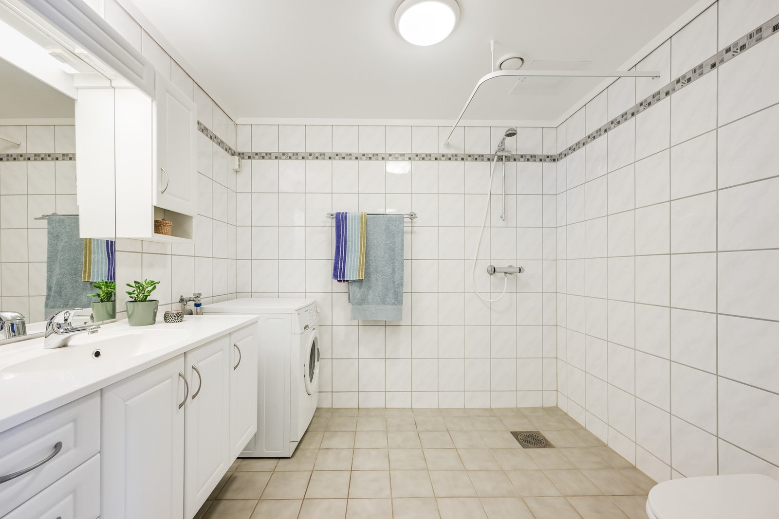 Et romslig og flislagt bad med gulvvarme Galleribilde