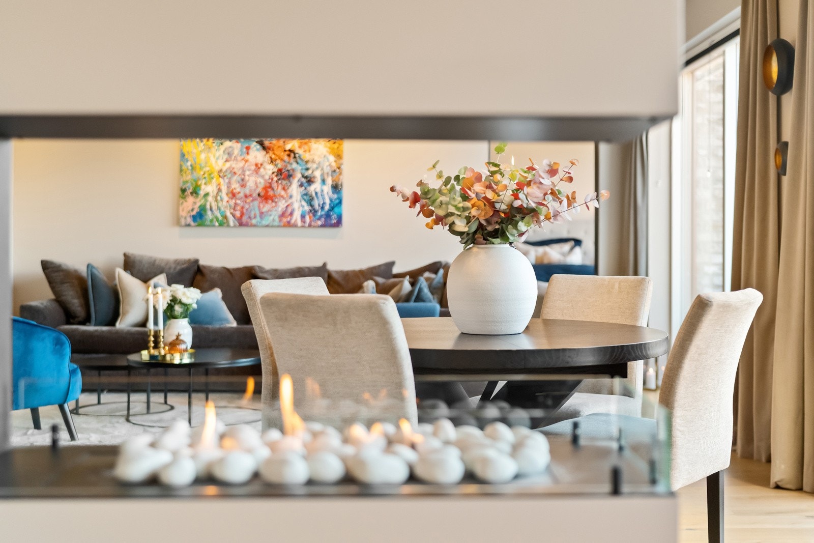 I deleveggen mellom stue og kjøkken ble det installert en lekker biopeis i 2024 med glass på sidene og åpen flamme, et lunt og stilig blikkfang. Galleribilde