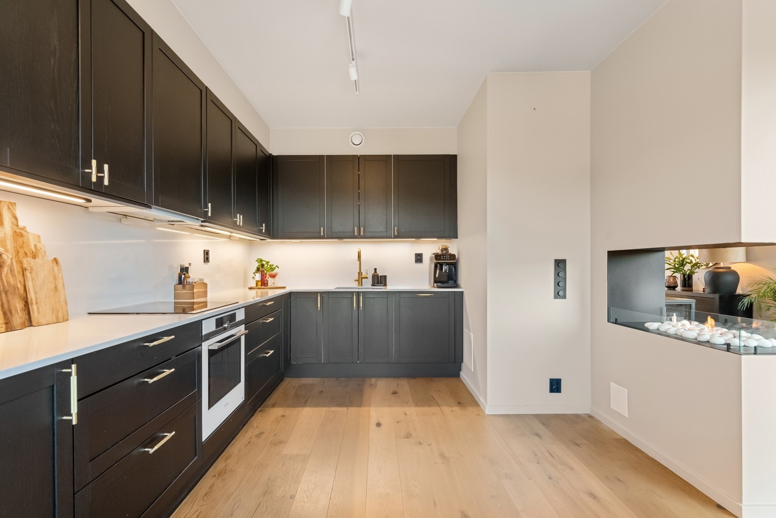 Samtidig ble kjøkkenet påkostet med nye fronter i sort trestruktur fra Norema, eksklusive messinghåndtak og tynn benkeplate i lys steinkompositt. Galleribilde