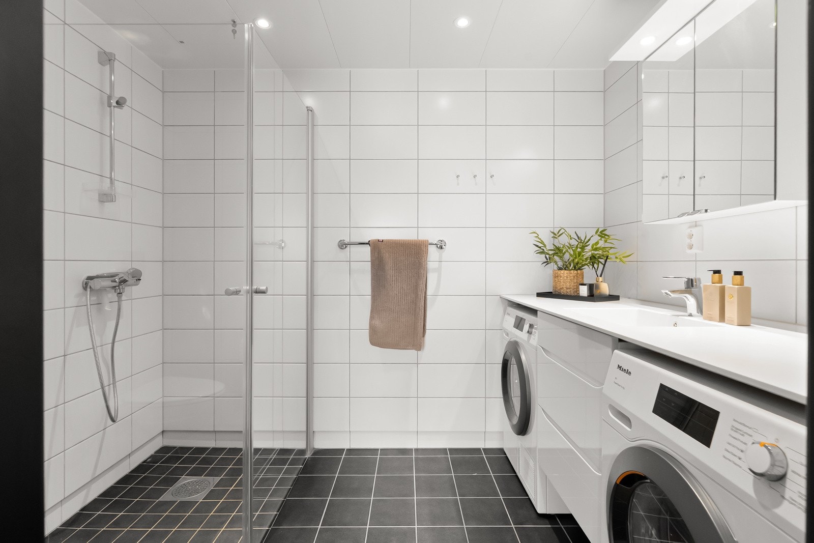 Dette er også et kombinert vaskerom med opplegg og plass til vaskemaskin og tørketrommel under benkeplaten i Corian. Galleribilde