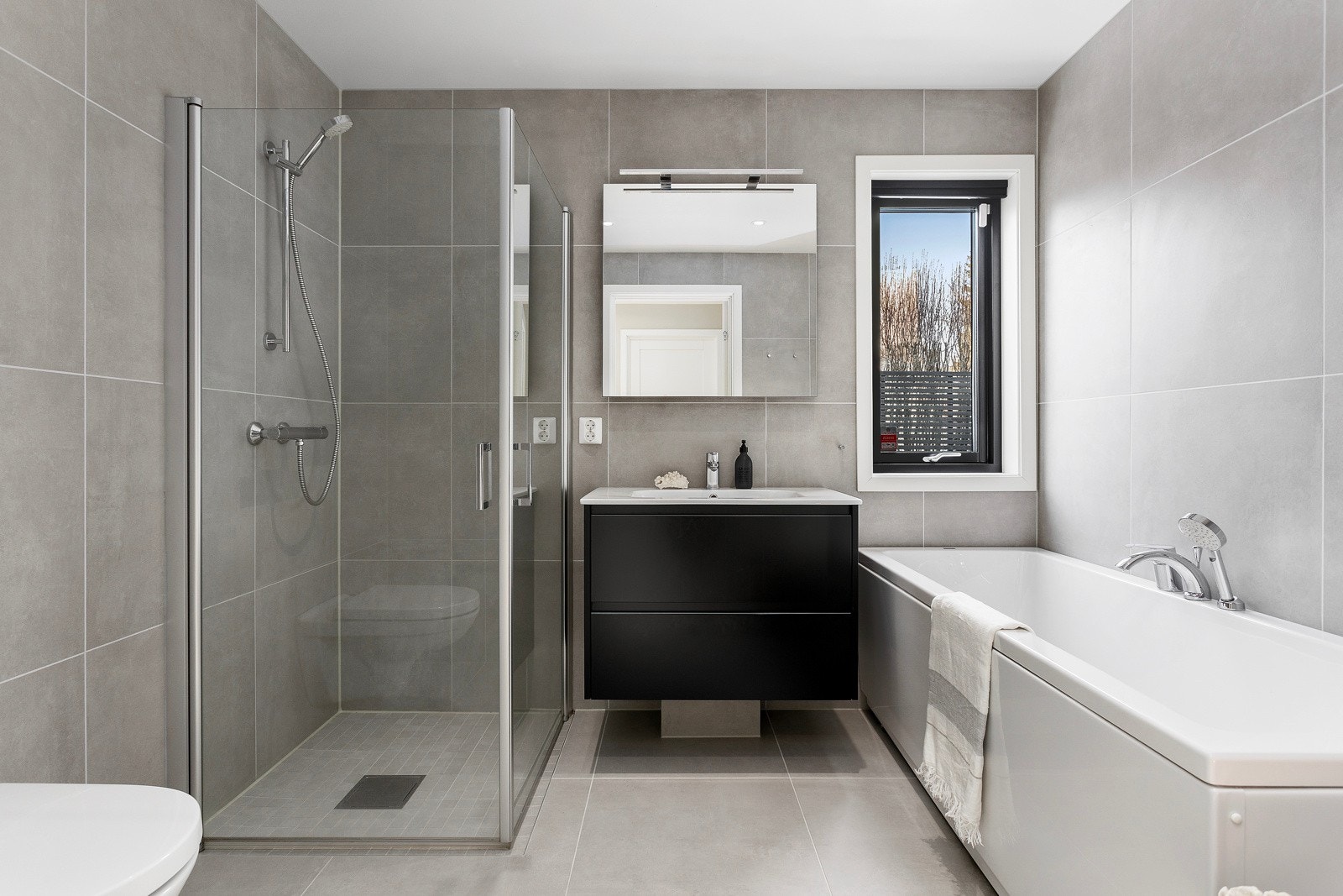 I inngangsetasjen ligger også et moderne bad med minimalistisk innredning i likhet med kjøkkenet og de andre badene i huset, noe som gir en rød tråd igjennom hele Galleribilde