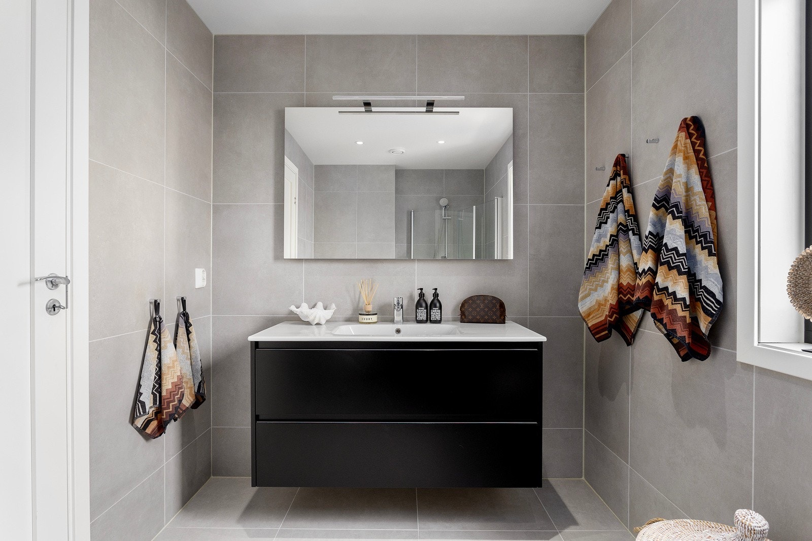 Badet har minimalistisk innredning med 60x60 fliser både på gulv og vegger, behagelig varme i gulvet og downlightsbelysning. Galleribilde