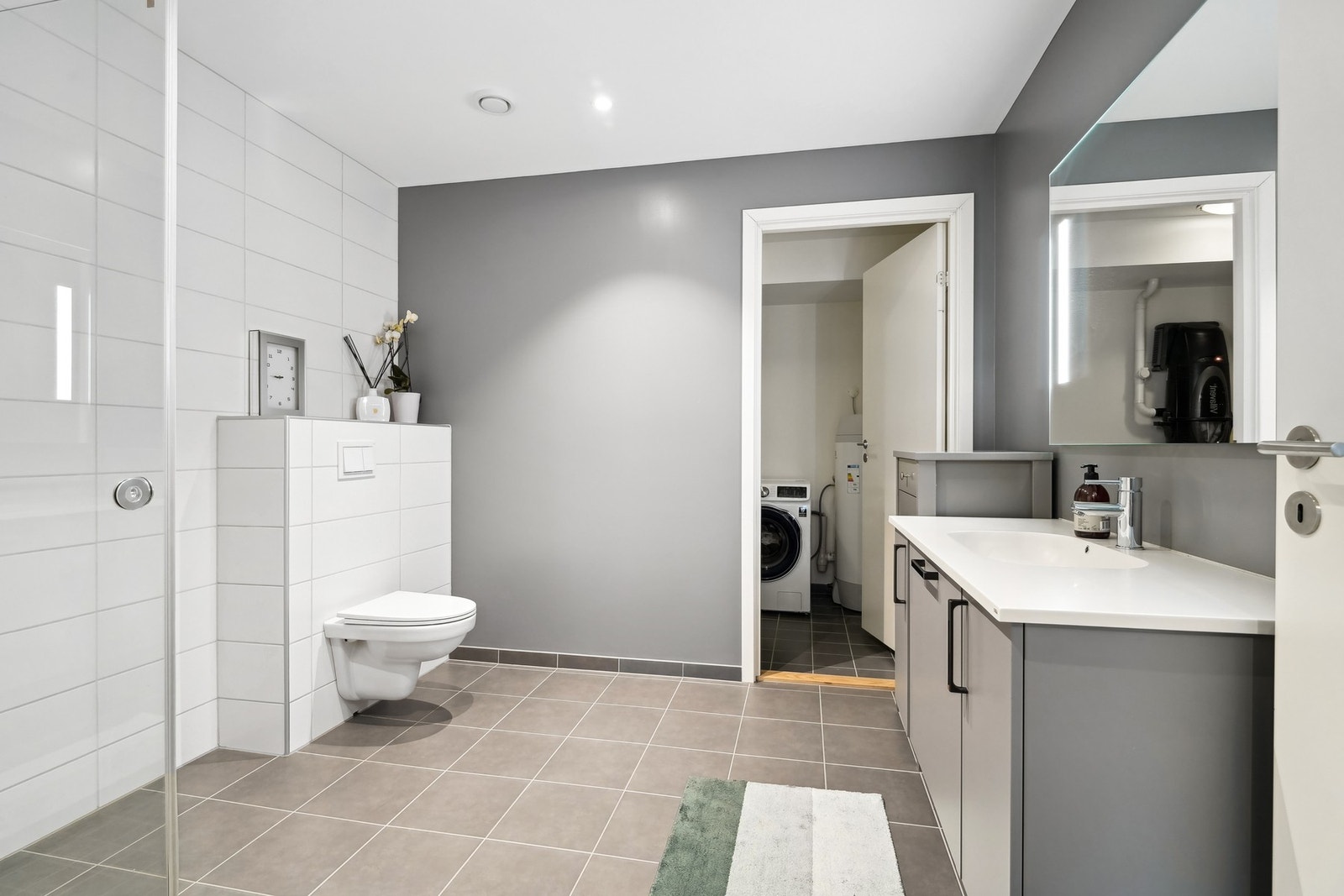 Flott bad med flislagt gulv og vegger, samt gulvvarme. Praktisk plassert vaskerom rett ved siden av. Galleribilde