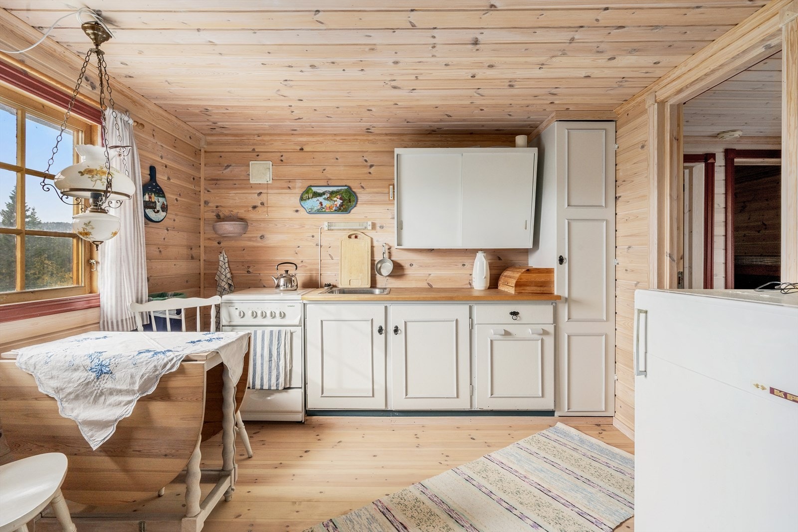 Enkelt hyttekjøkken med avsatt plass for komfyr og kjøleskap. Galleribilde