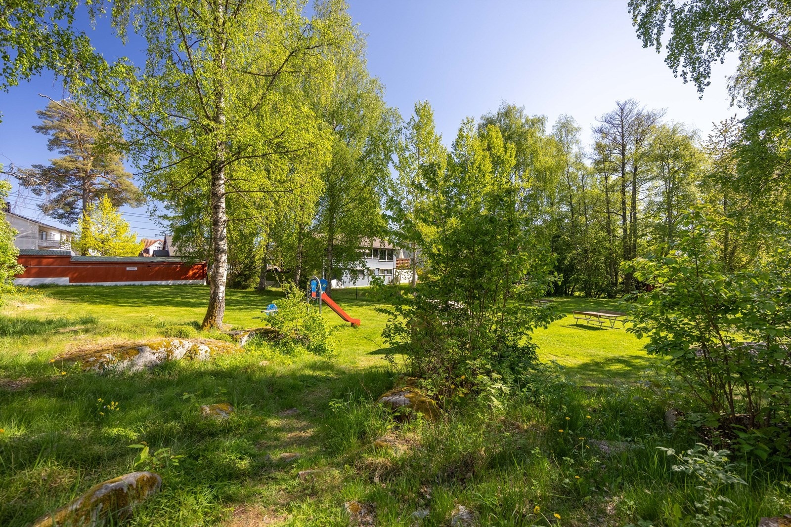 Pent opparbeidet fellesområde med lekeapparater og sittebenker i skjermede omgivelser Galleribilde