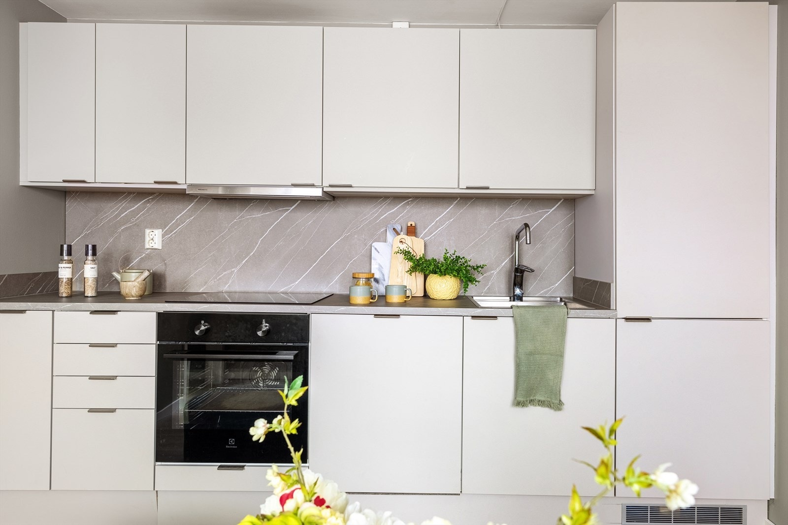 Kjøkkenet har innredning med slette fronter, laminat benkeplate, stål oppvaskkum og ventilator Galleribilde