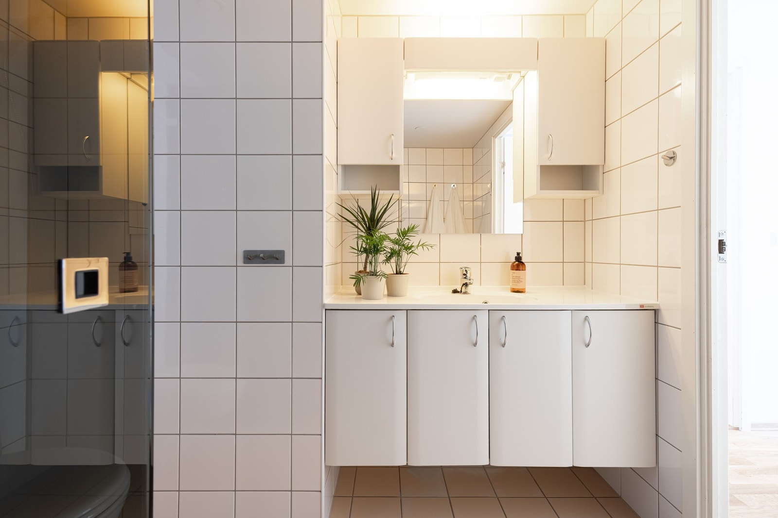 Badet består av baderomsinnredning med servant, speil med belysning, dusjhjørne med glassdører og vegghengt toalett. Galleribilde