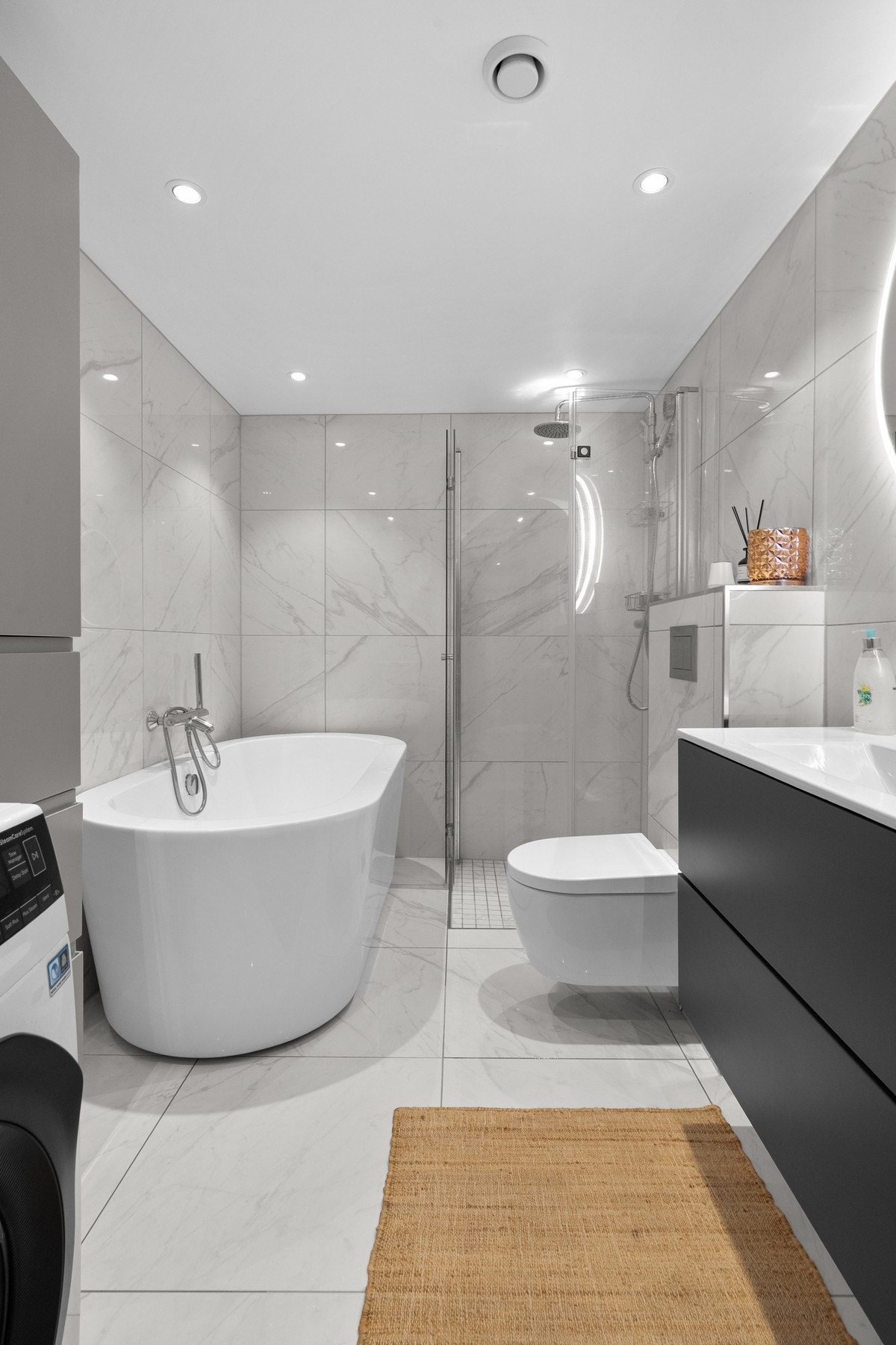 Baderommet har vegghengt toalett, moderne servant og flislagte vegger og gulv Galleribilde