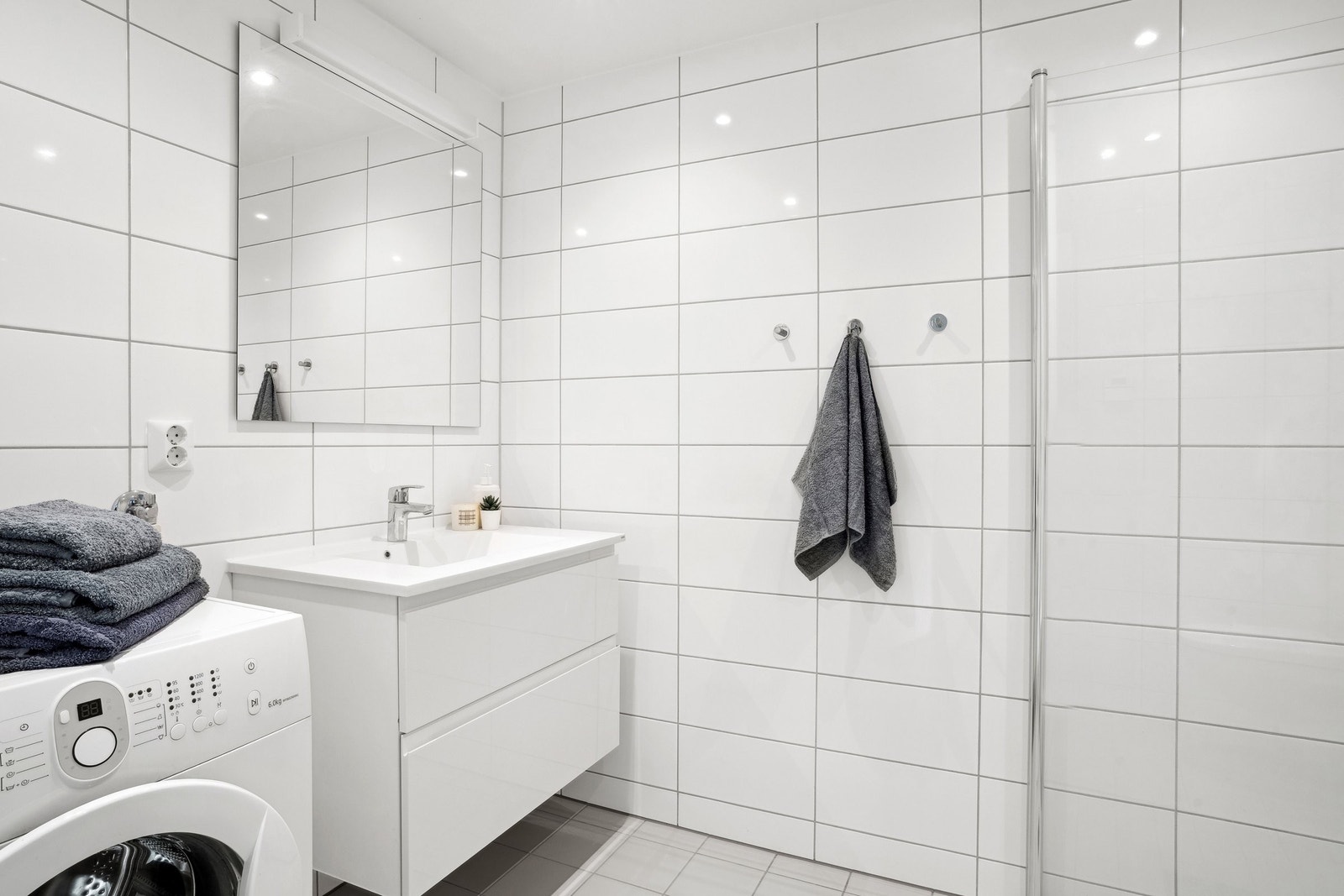 Badet har dusjhjørne med innfellbare glassdører, vegghengt WC, servantskap og opplegg for vaskemaskin. Galleribilde
