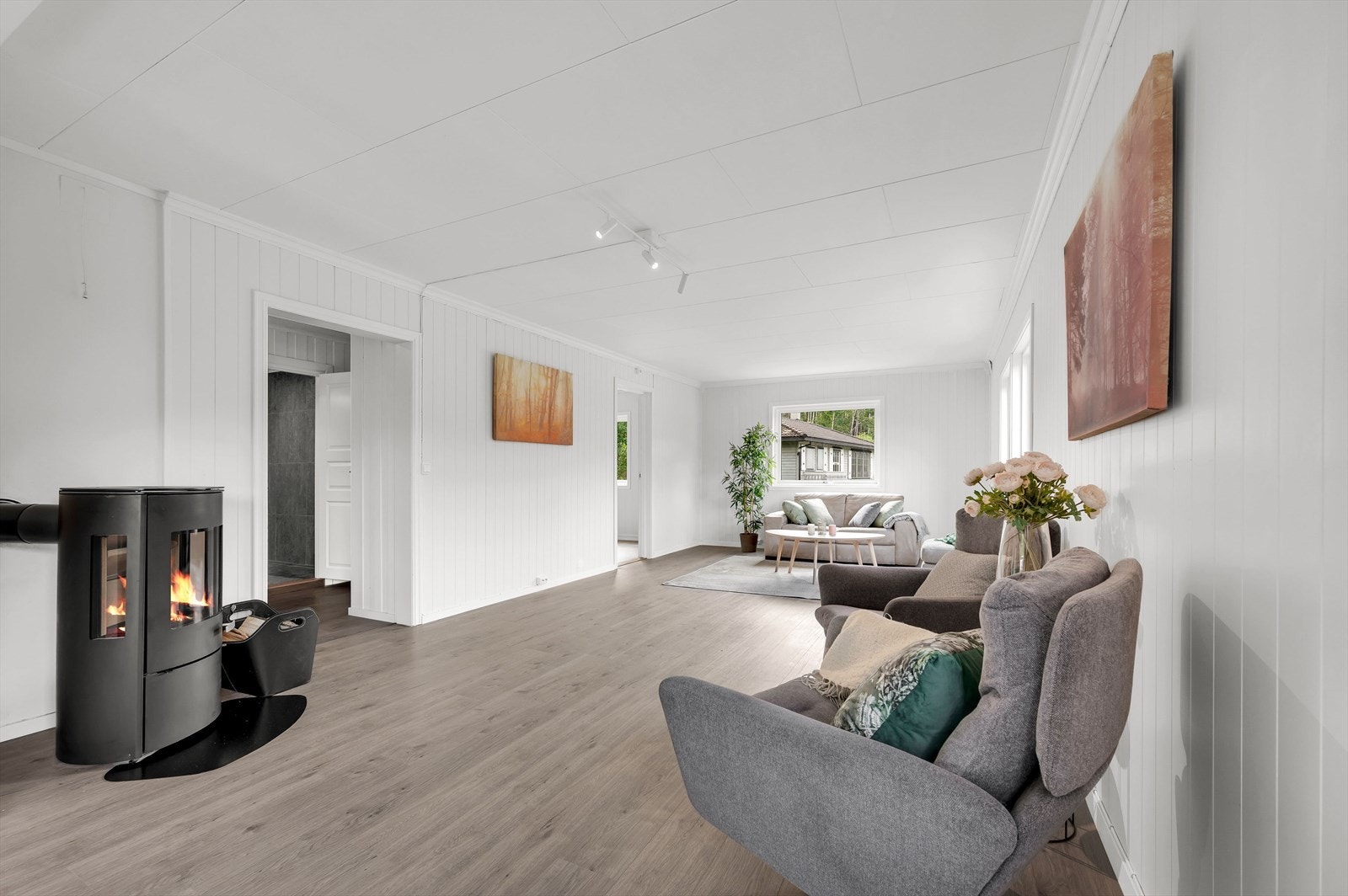 Romslig og lys stue med koselig peisovn Galleribilde