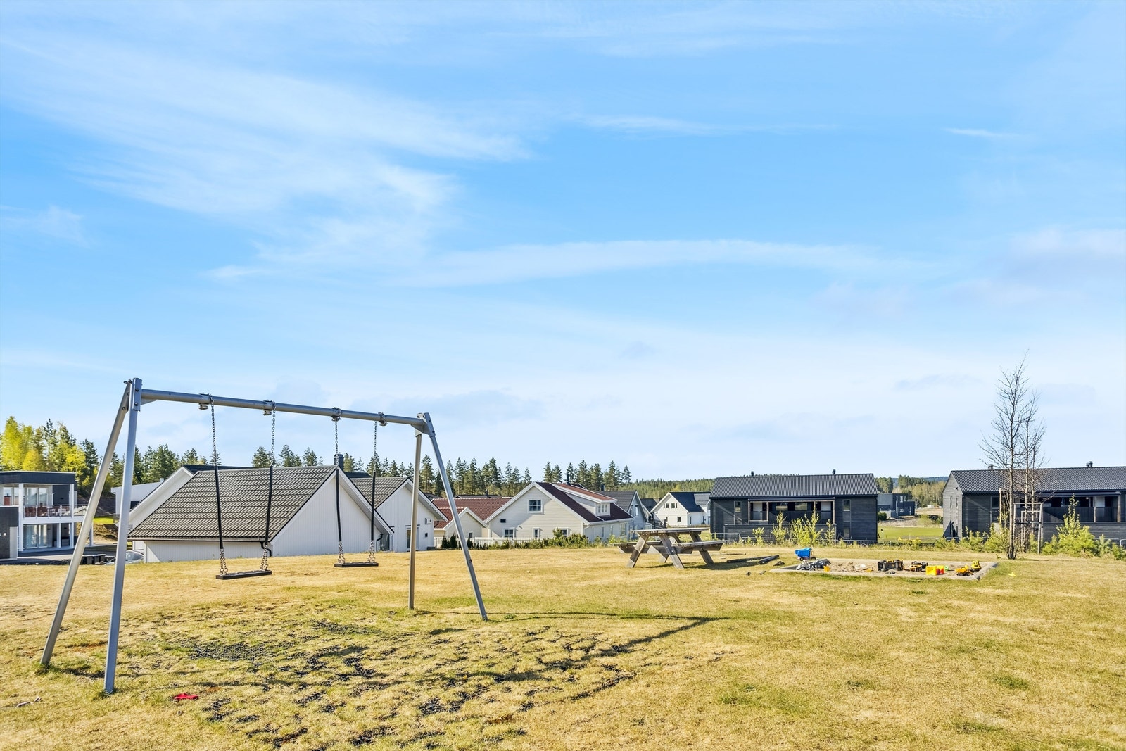 Lekeplass på fellesareal med huskestativ, benk og sandkasse Galleribilde