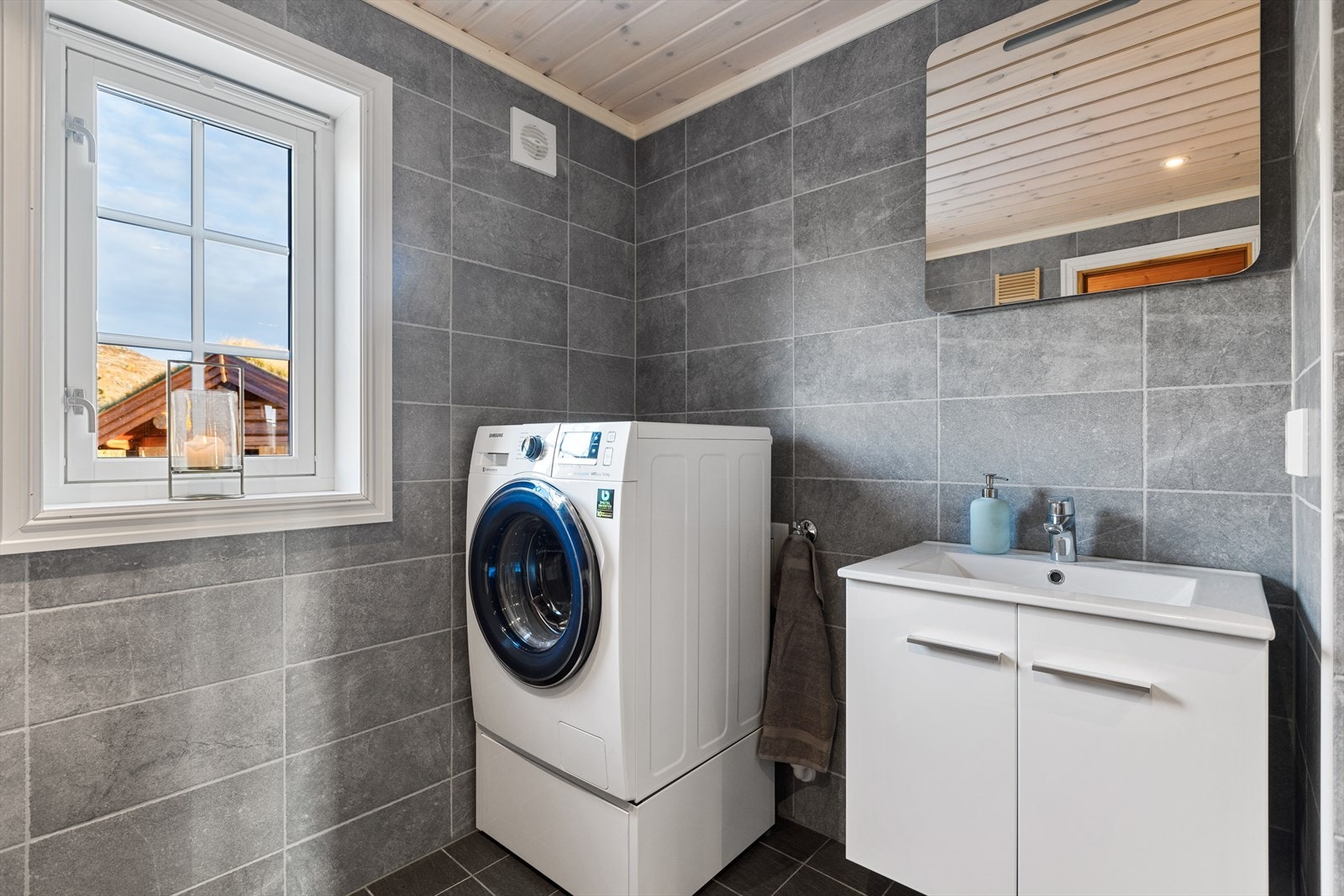 Badet er innredet med toalett, servantinnredning, dusjvegger og opplegg til vaskemaskin. Galleribilde