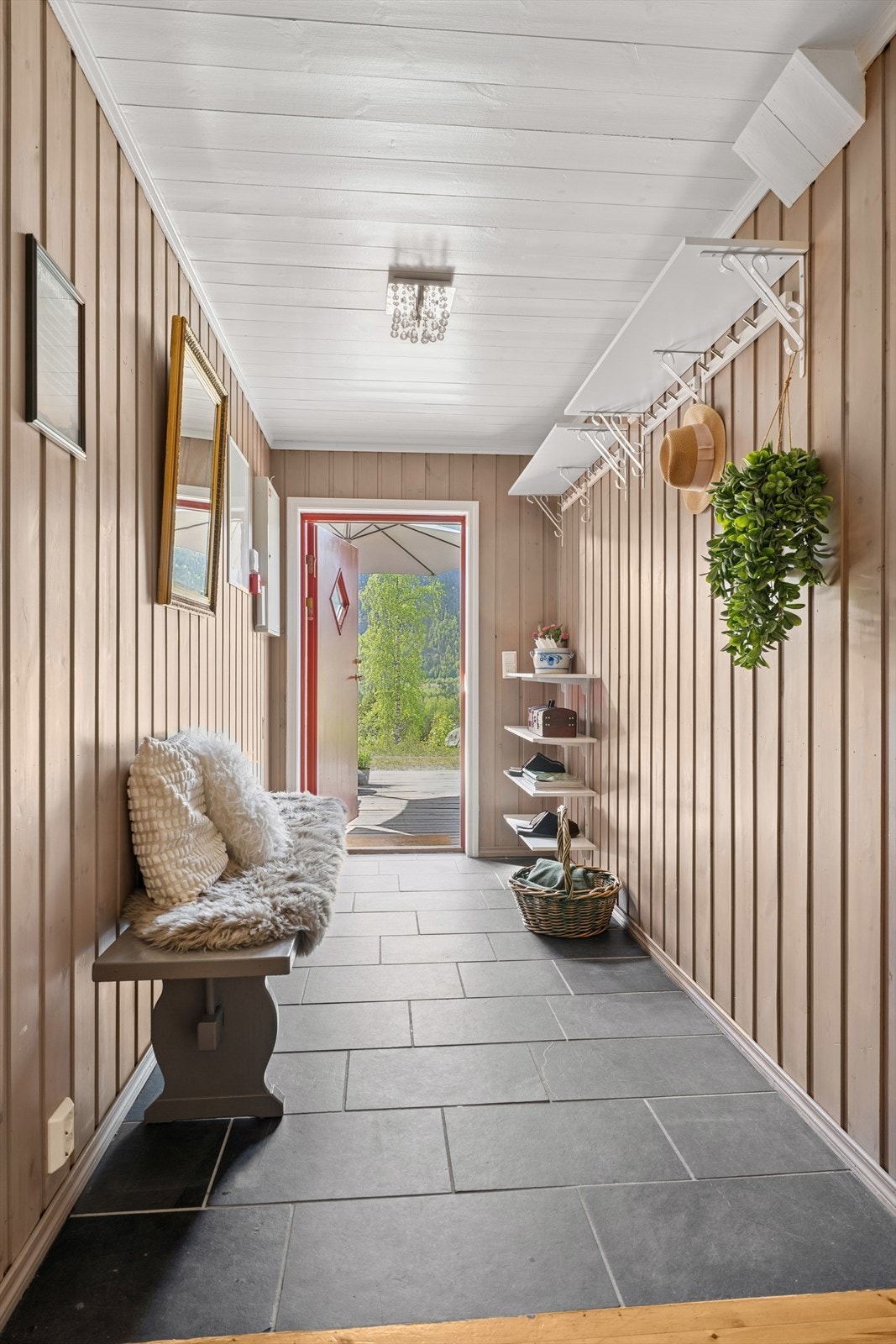 Innenfor døren til leiligheten blir du møtt av en romslig entré/gang med fliser på gulvet og lysmalte vegger. Galleribilde