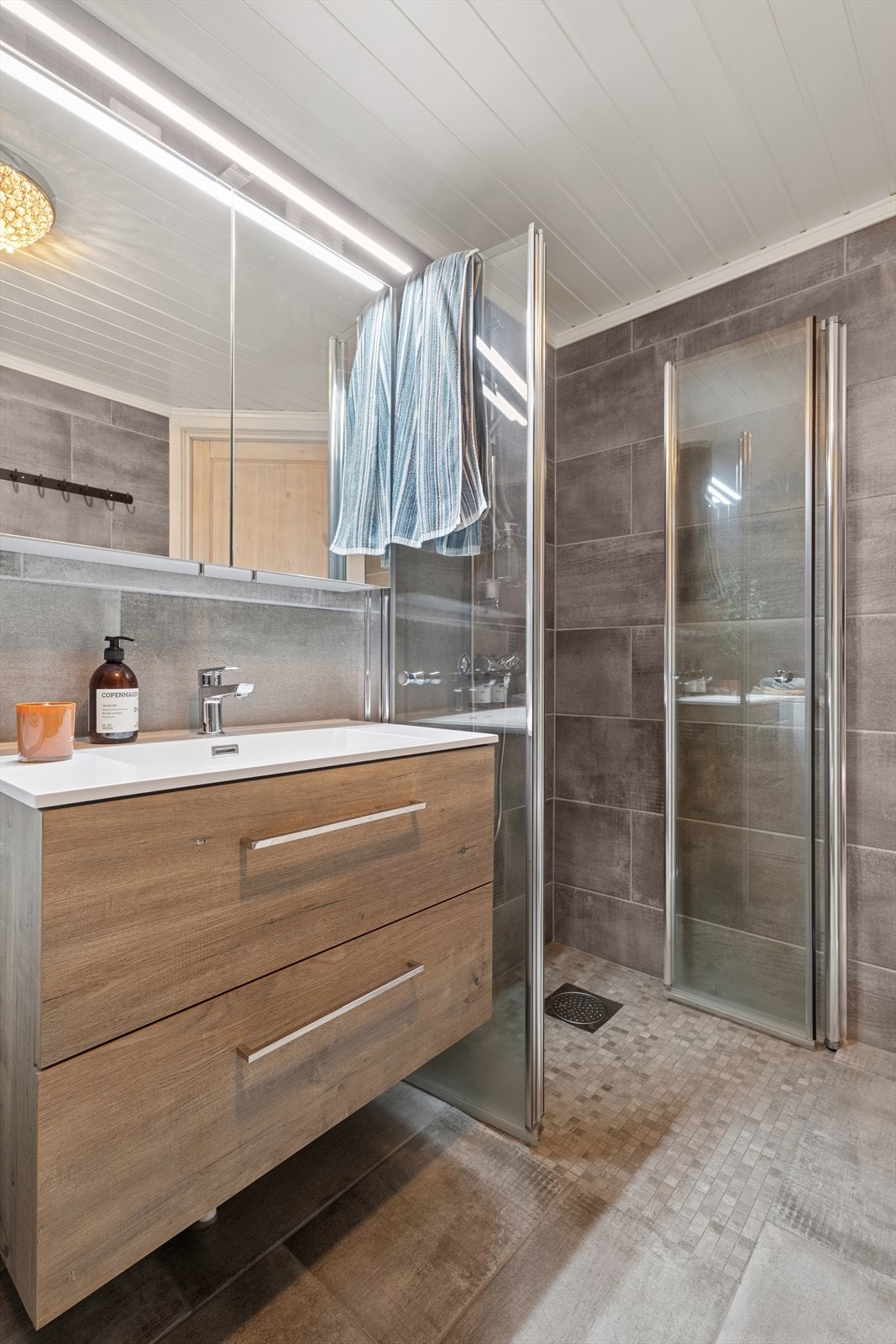 Baderomsinnredningen er pent utført med brune, glatte fronter og romslige skuffer, samt heldekkende servant. Galleribilde