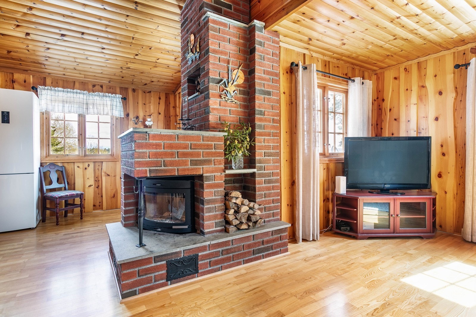 Stuens peis er orientert ut i rommet og er således til glede for både sofakroken, spisebordet og kjøkkenet. De fleste møbler medfølger. Galleribilde