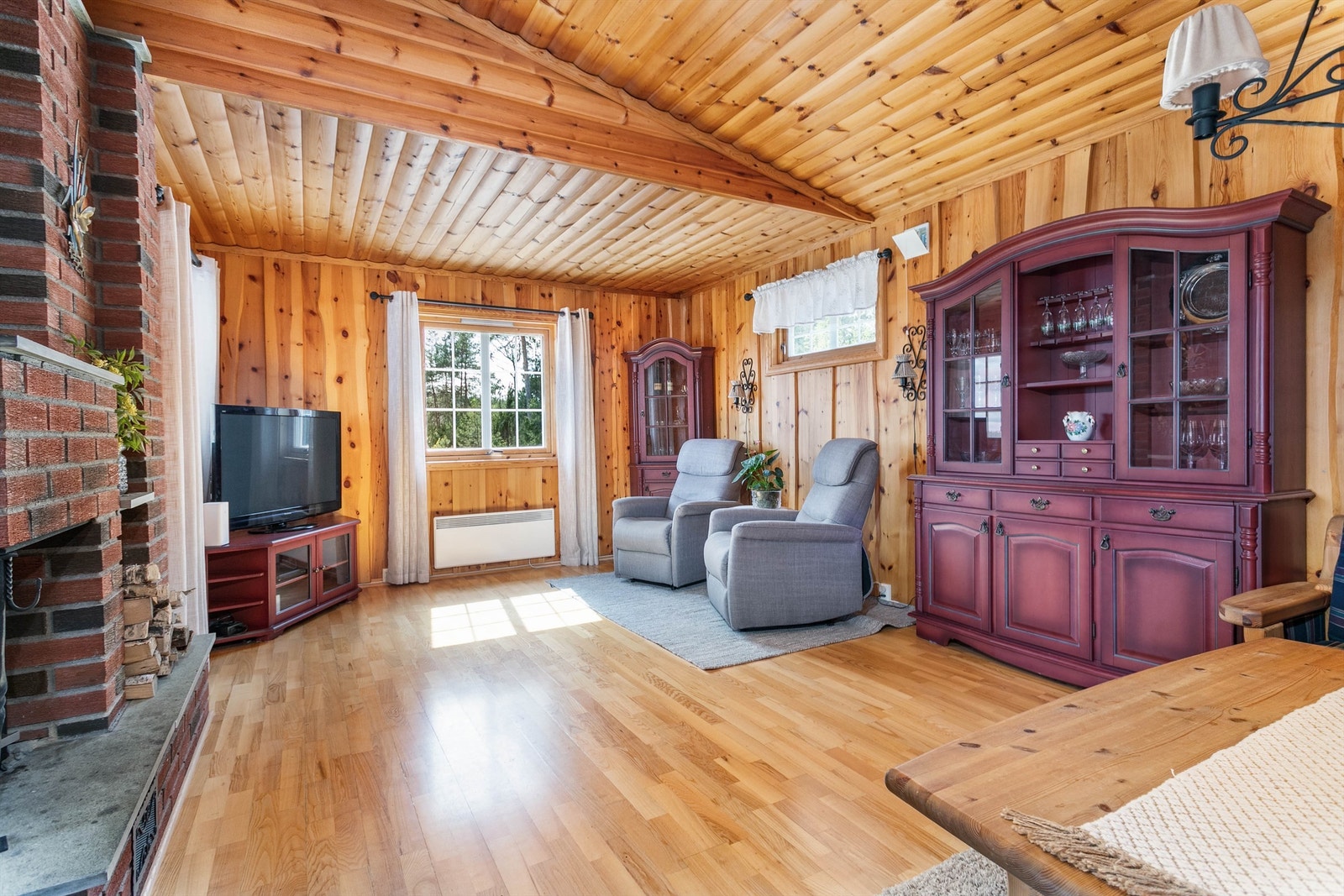 Naturlige overflater av heltre gir hyttas indre en lun og trivelig atmosfære. Villmarkspanel pryder stuens vegger. Galleribilde