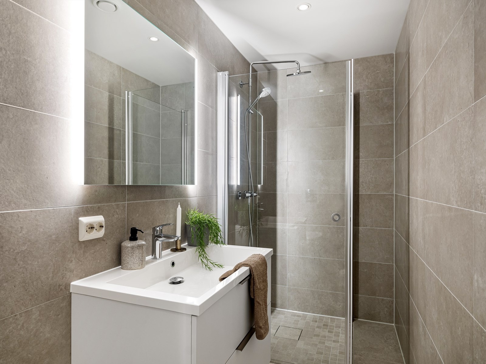 Leilighetens andre bad med tilkomst fra gang. Badet er innredet med vask i seksjon, speil med belysning, veggehengt toalett og foldbare dusjdører i glass. Galleribilde