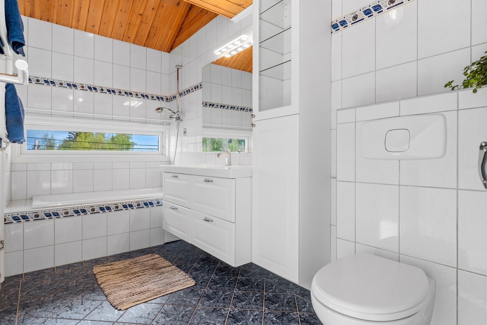 Badet i hoveddelen er helfliset, innredet med badekar, varmekabler og vegghengt toalett. Galleribilde