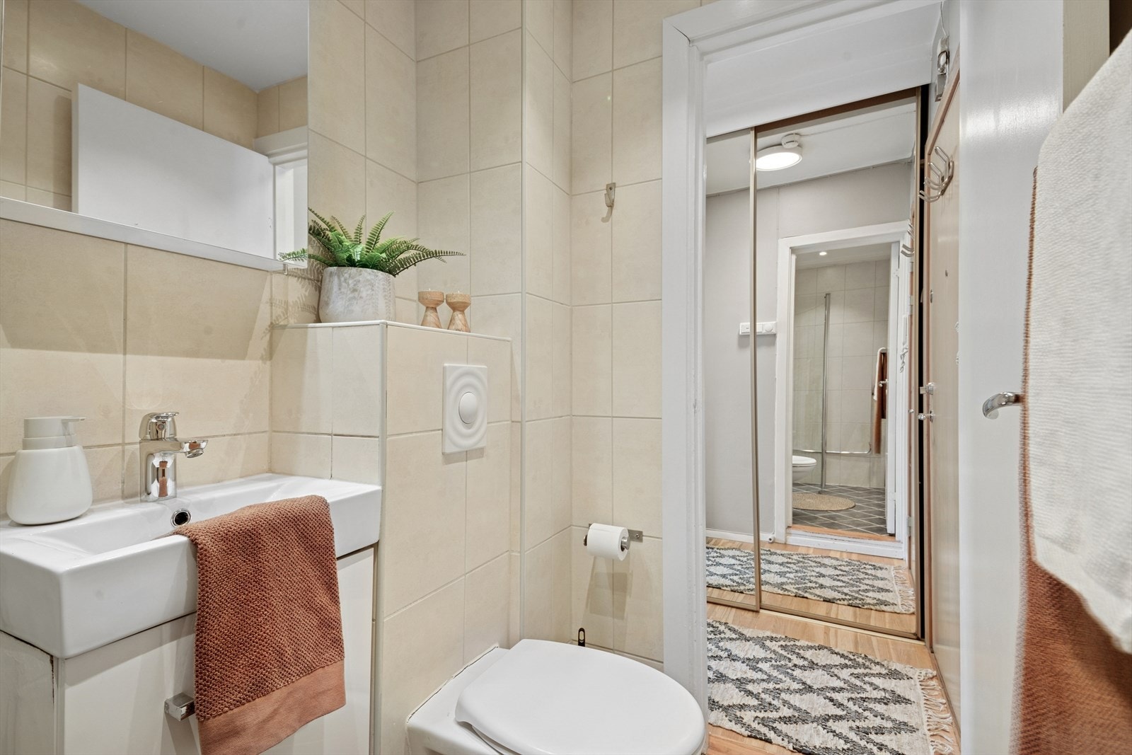 Her er det dusj på gulv med dører i herdet glass, veggfestet klosett med innebygget sisterne, servant, opplegg for vaskemaskin, benkeskap med glatte fronter, samt overskap med speilfronter og belysning over servant. Galleribilde