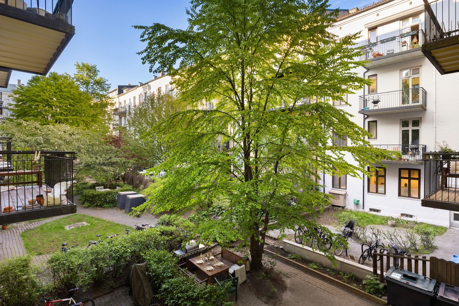 Den grønne og frodige bakgården med har sittegrupper og sykkelparkering. Et perfekt uteområde for avslapning og sosiale sammenkomster midt i byen Galleribilde