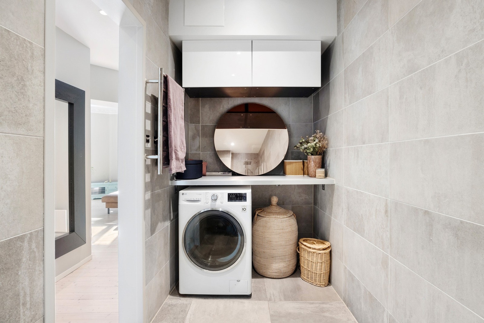 Badet har en praktisk og moderne vaskesone med integrert opplegg for vaskemaskin. Flott benkeplate over vaskemaskinen gir ekstra arbeidsflate, og veggskap gir god oppbevaringsplass Galleribilde