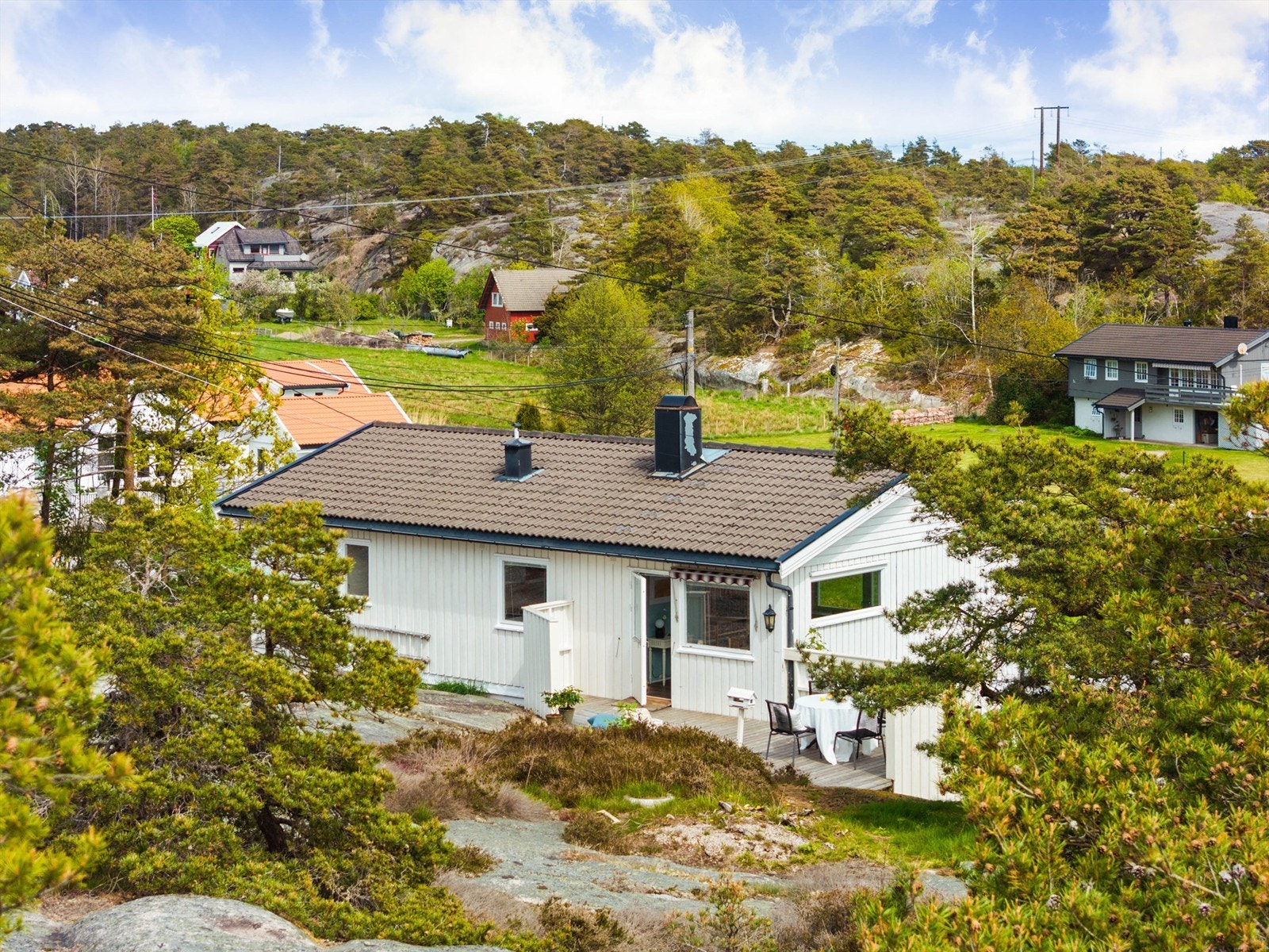 Ovenfor boligen strekker tomten seg nesten 18 meter opp i skråningen bestående av barfjell og naturlig vegetasjon. Galleribilde