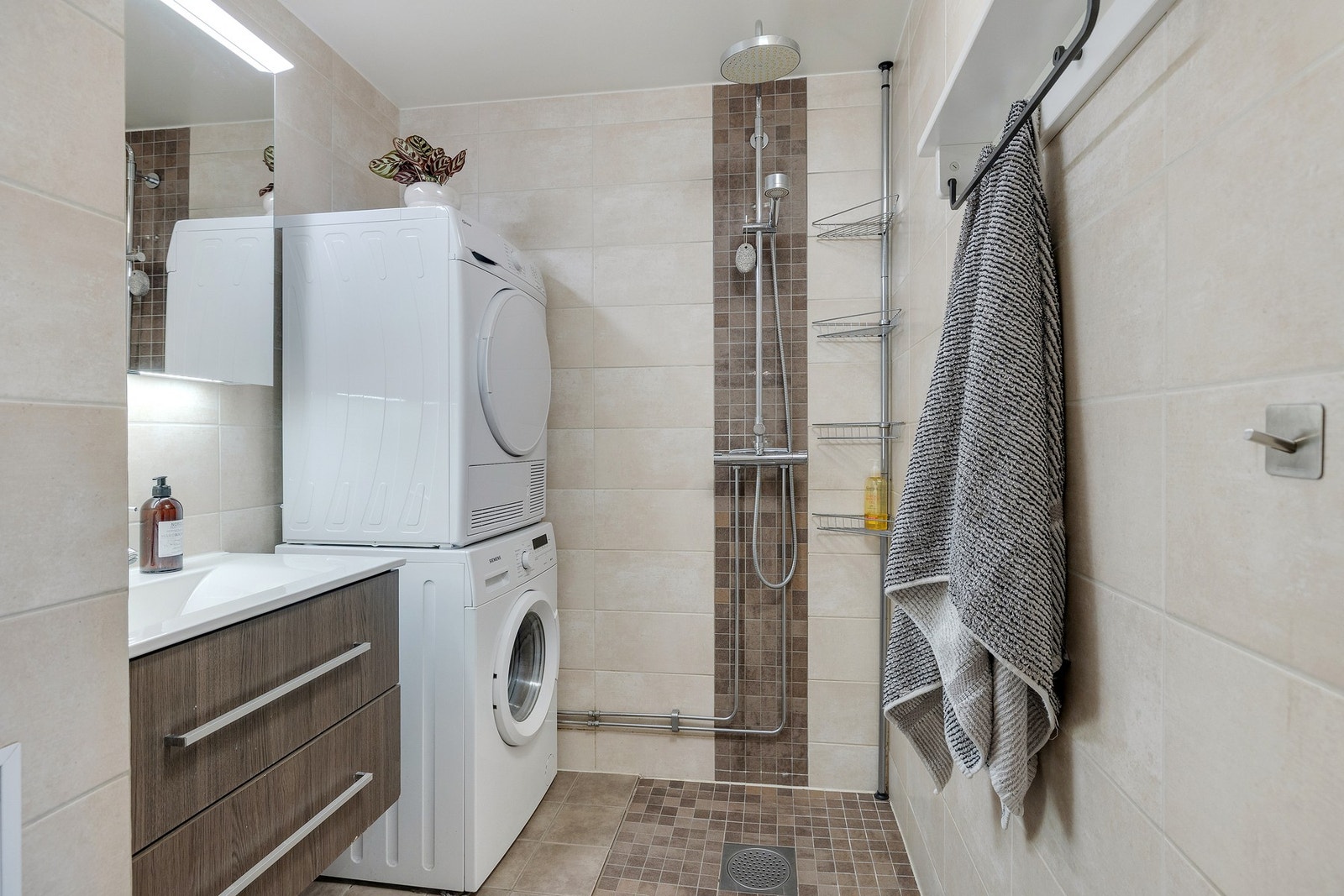 Lekkert, flislagt bad med opplegg for vaskemaskin og tørketrommel. Galleribilde