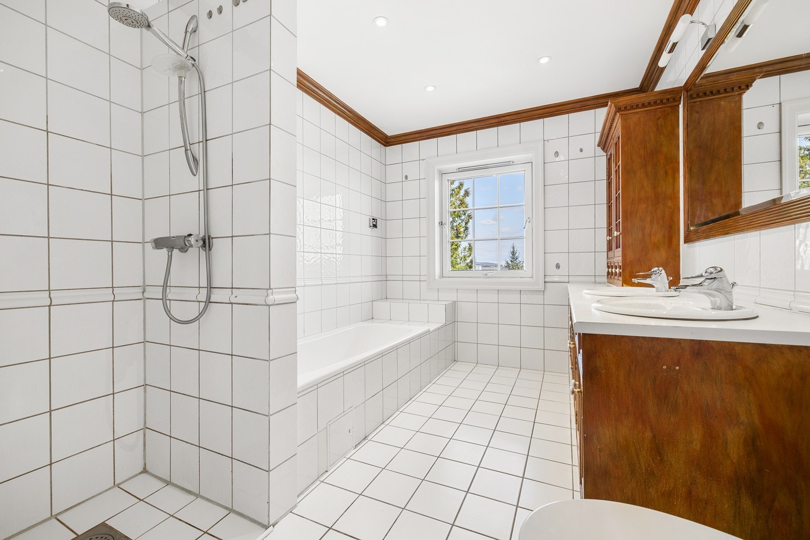 Lyst og pent flislagt bad med badekar og dobbel vask. Galleribilde