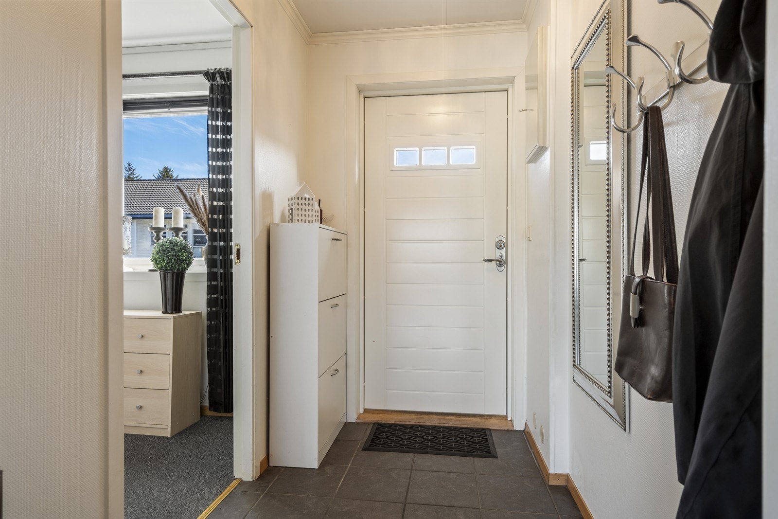 Vindfang med fliser på gulv og plass til å henge fra seg yttertøy. Galleribilde