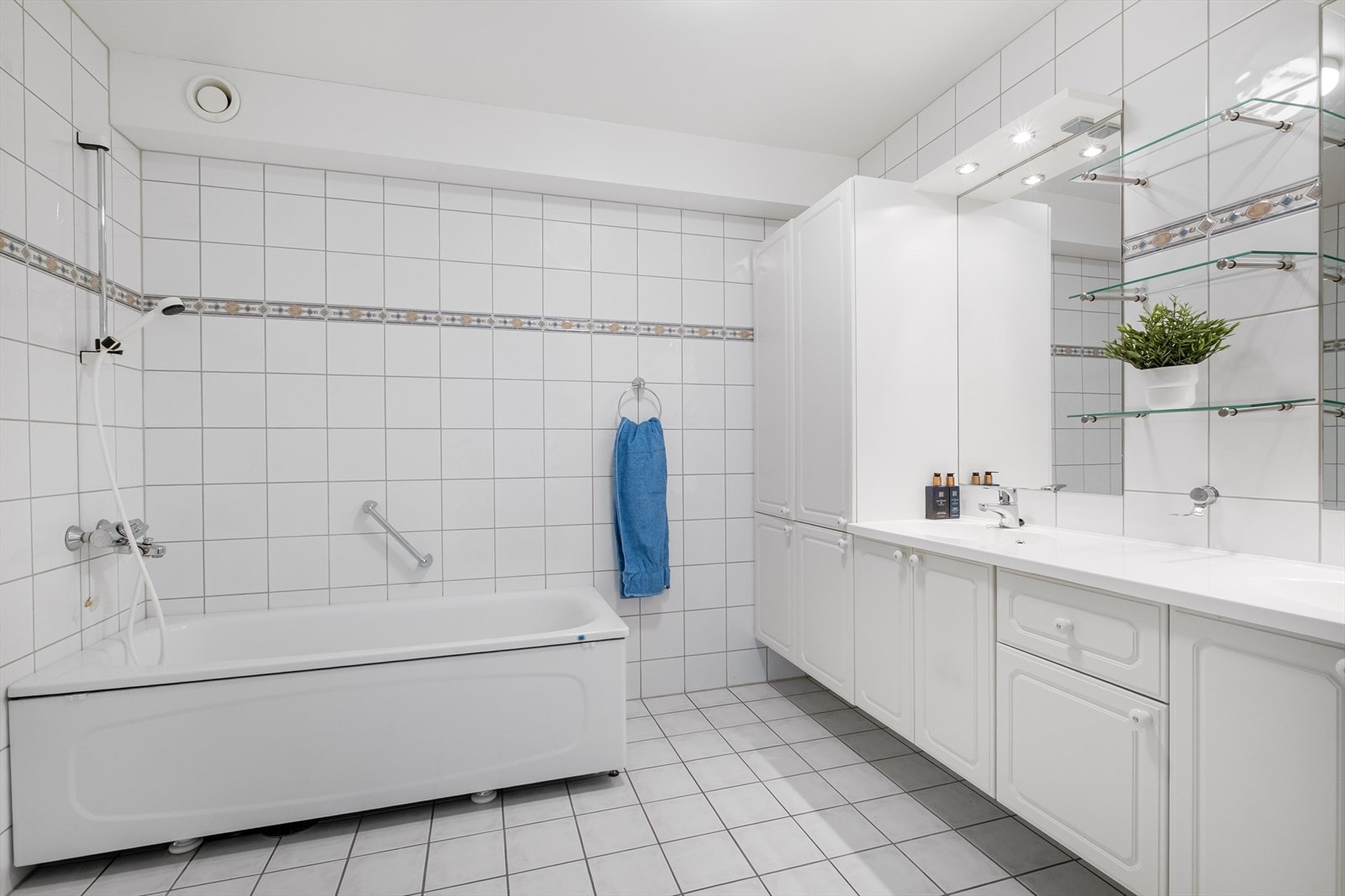 Masterbad innredet med badekar, dusjgarnityr, stor servant med skap og vegghengt toalett. Galleribilde