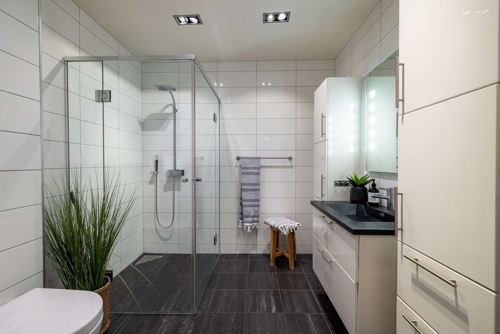 Flislagt bad mot øst med gulvvarme. Dusjhjørne med glassvegger og vegghengt dusjarmatur med hånddusj og regndusj. Vegghengt toalett Galleribilde