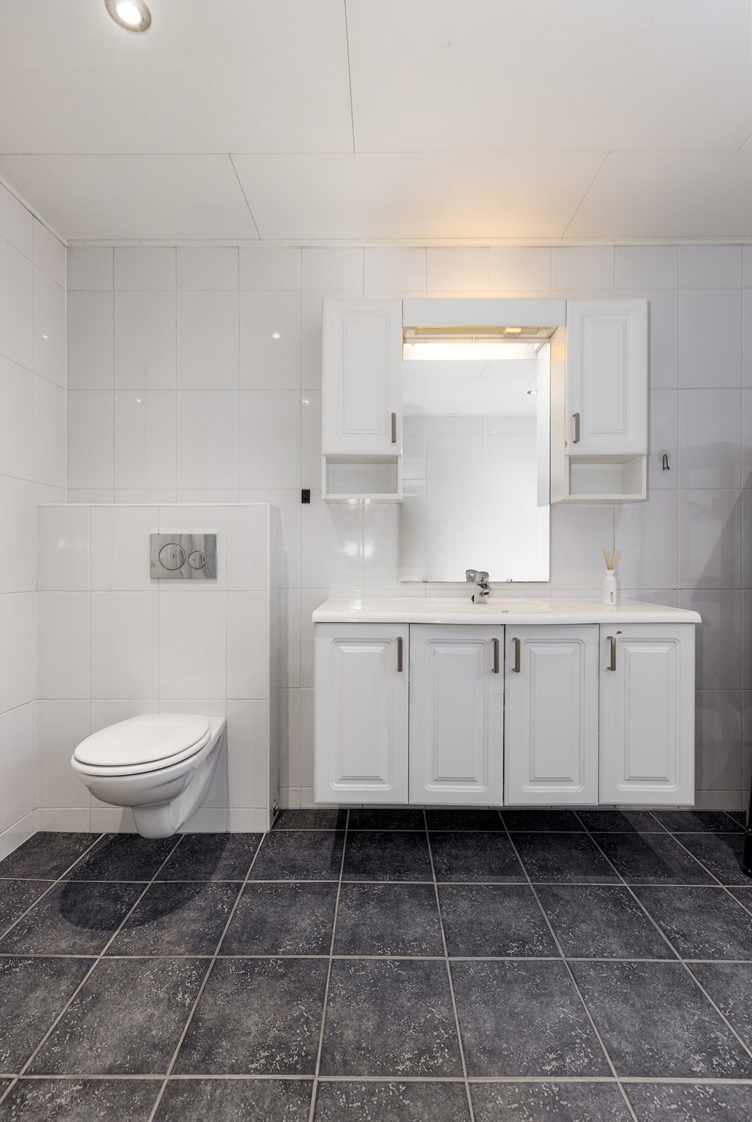 Badet er innredet med vegghengt toalett, badekar og dusjkabinett. Samt servantinnredning med underskap, overskap, speil og overlys med el-stikk. Galleribilde