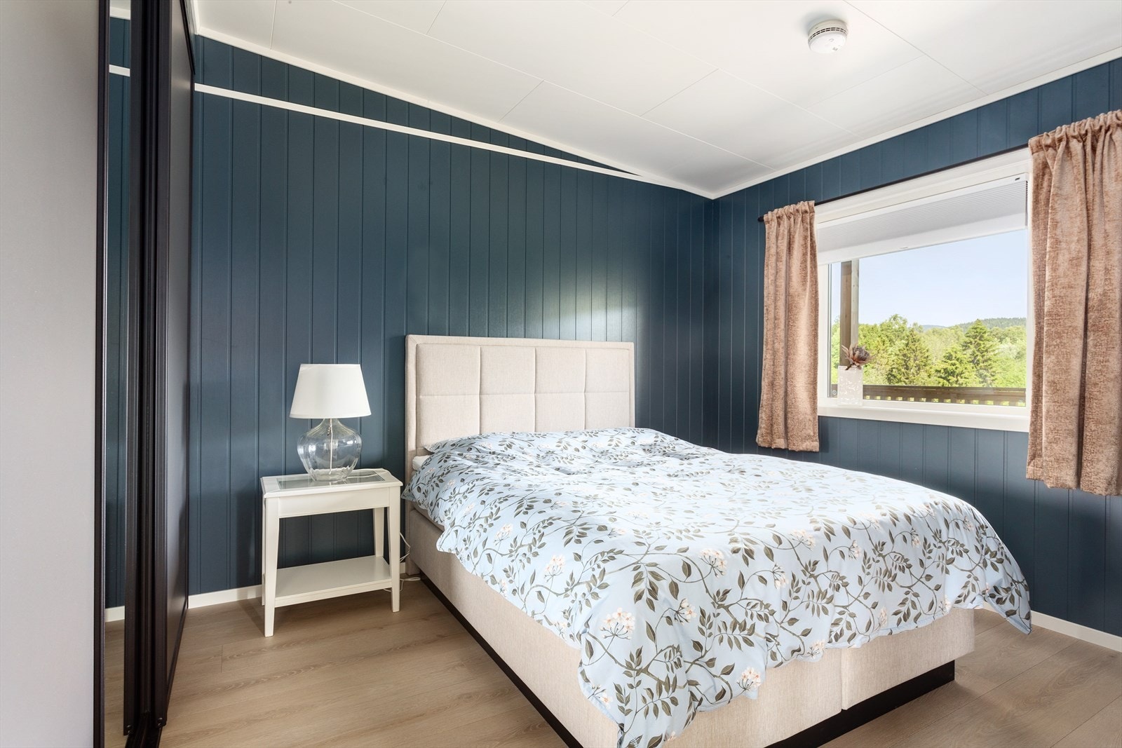 Soverom med stor skyvedørsgarderobe på hele veggen til venstre. Rommet har god størrelse med plass til 1,80 seng med tilbehør. Ellers er rommet malt i en dempet og behagelig blåfarge. Galleribilde