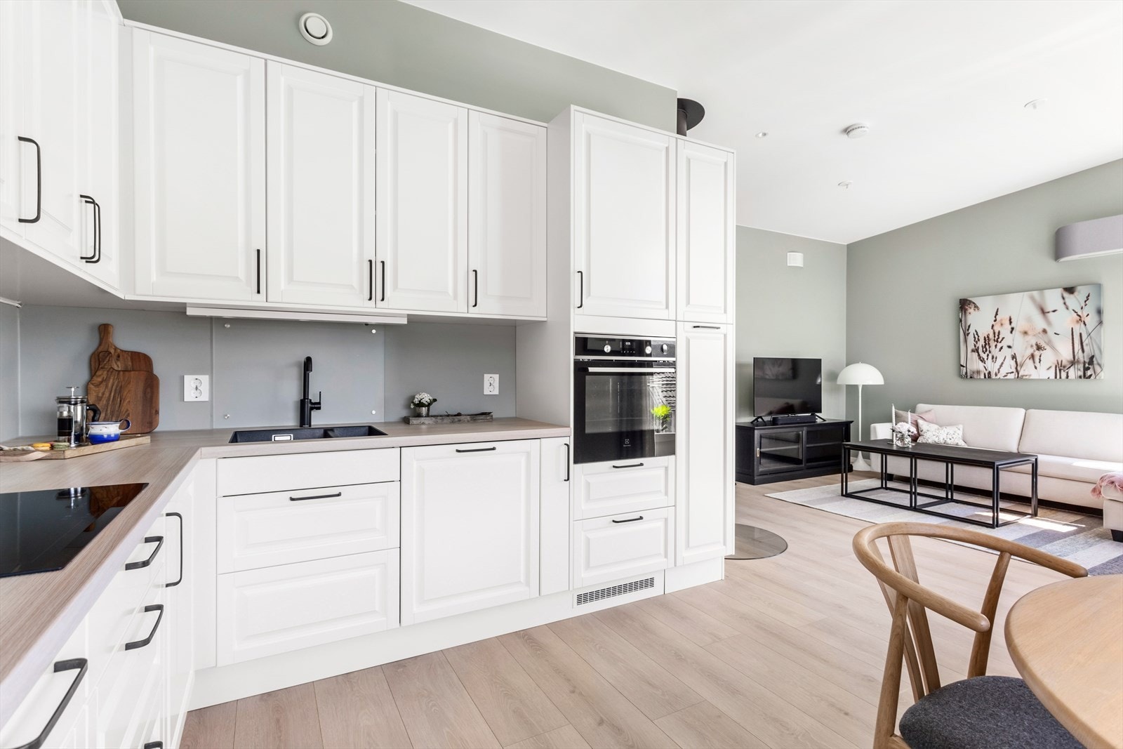 Glassplater er montert over oppvaskkum og platetopp for å forhindre at smuss og fett treffer direkte på veggen. Den duse grønnfargen på veggen er gjennomgående og binder rommene fint sammen. Galleribilde