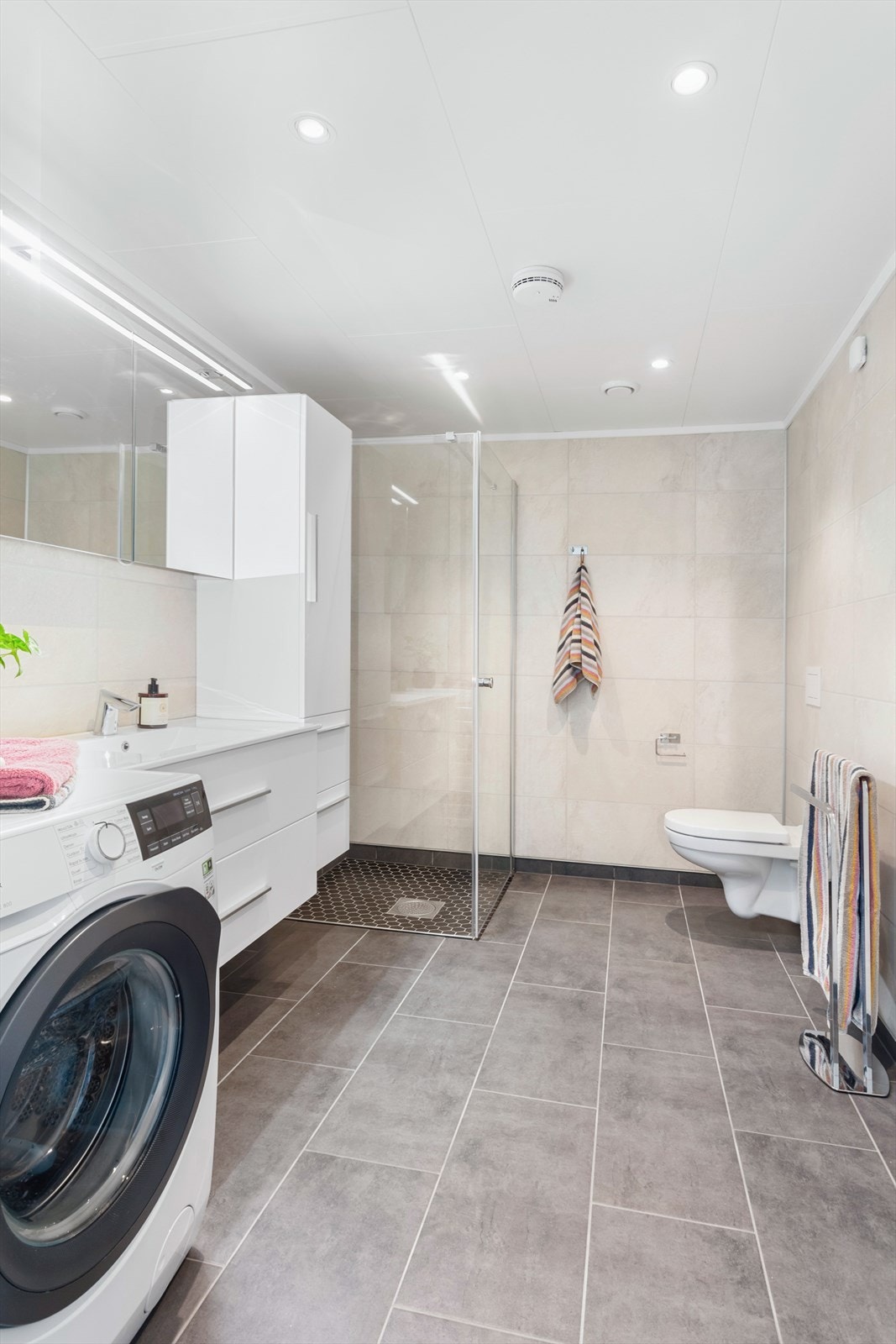 Lekkert bad som inviterer til velvære. Det er lagt baderomsplater på veggene, mens gulvet er flislagt. Dusjhjørne med mosaikkfliser på gulvet, og plass og opplegg for vaskemaskin. VVS-bereder m.m. er plassert på innvendig bod som er oppbygd som våtrom. Galleribilde