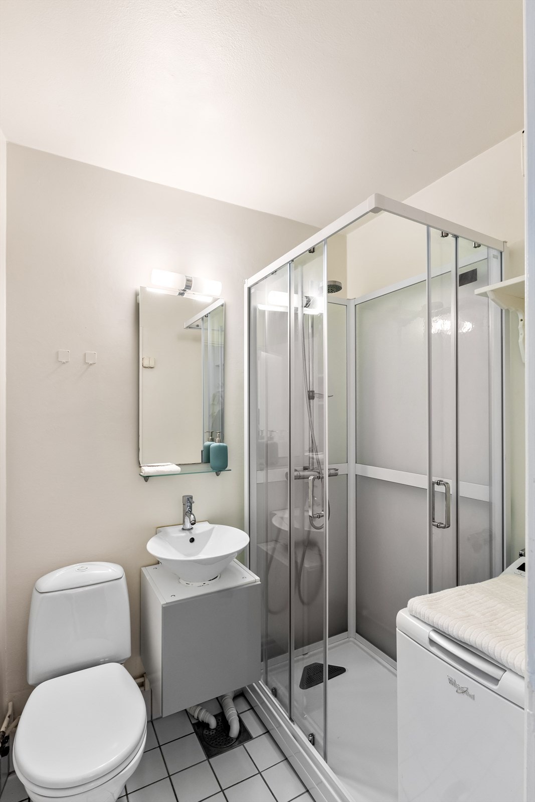 Flislagt bad innredet med nytt dusjkabinett 2020. Gulvstående klosett, servant og opplegg for vaskemaskin. Galleribilde