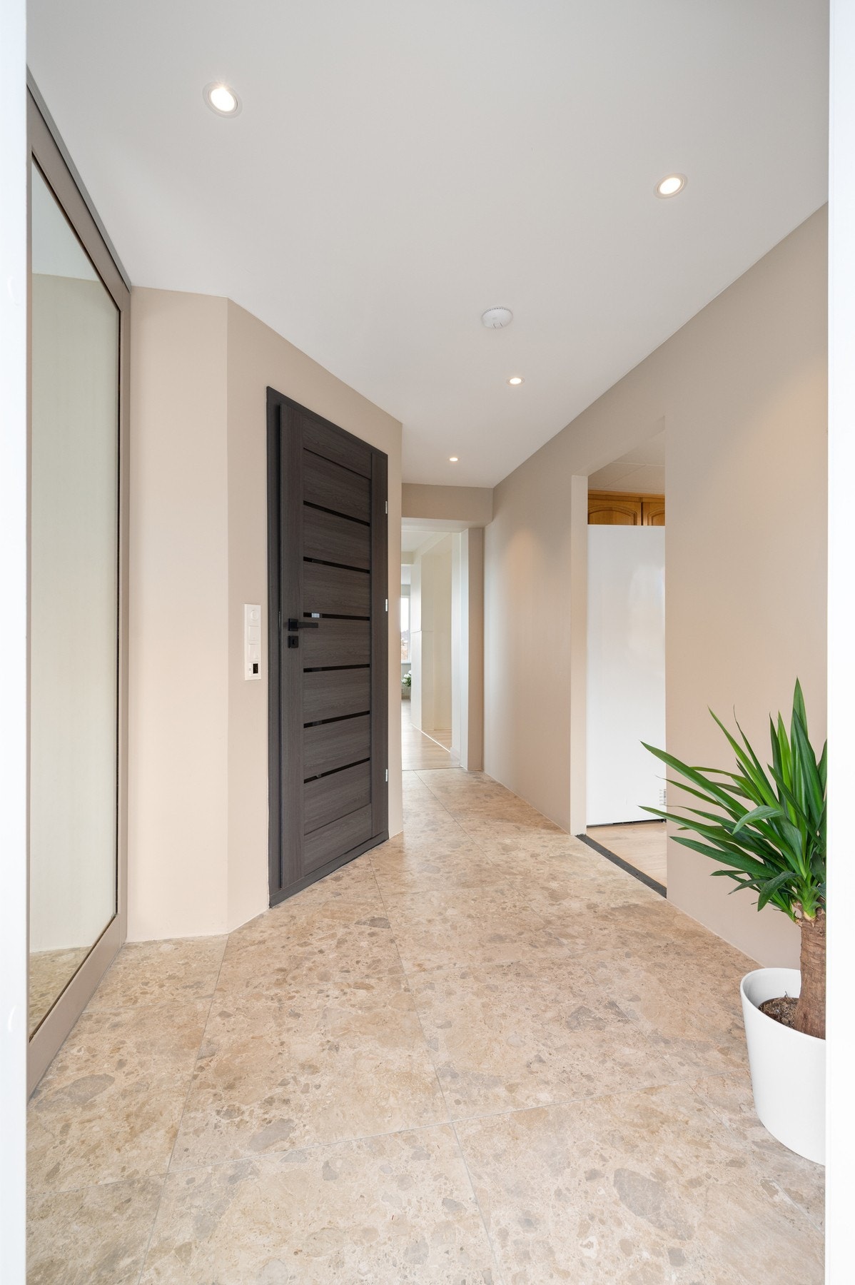 Flislagt gulv i entré med varme og en stor skyvedørsgarderobe til venstre Galleribilde