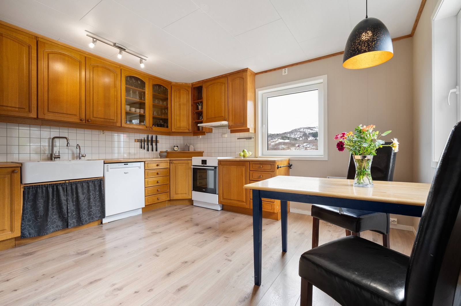 Kjøkkenet er stort og romslig med seksjonsinnredning - takhøye overskap med profilerte fronter Galleribilde