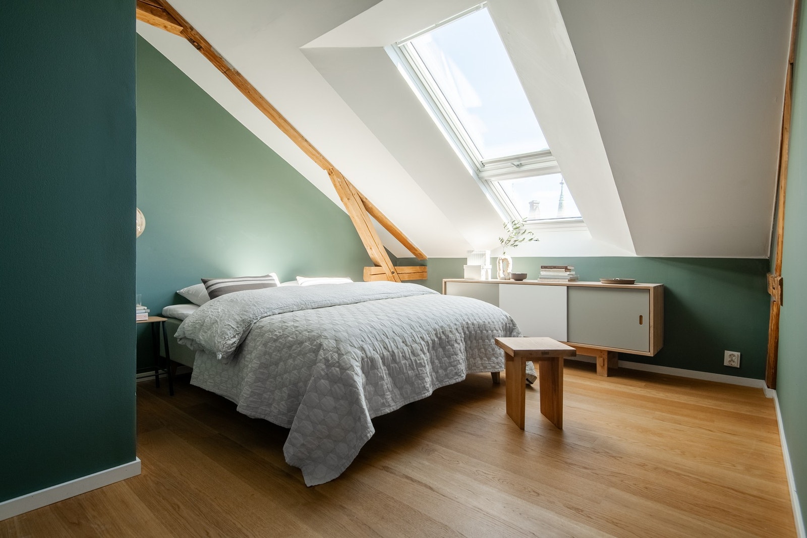 Hovedsoverommet bærer preg av den samme sjarmerende stilen som resten av boligen, med synlige takbjelker og generøs takhøyde som skaper en luftig og innbydende atmosfære. Galleribilde