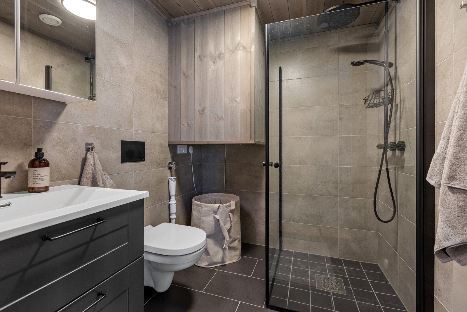 Pent flislagt bad med varme i gulv. Badet er innredet med dusjvegger, servant med underskap, speilskap og opplegg for vaskemaskin. Flott innkassing av varmtvannsbereder. Galleribilde