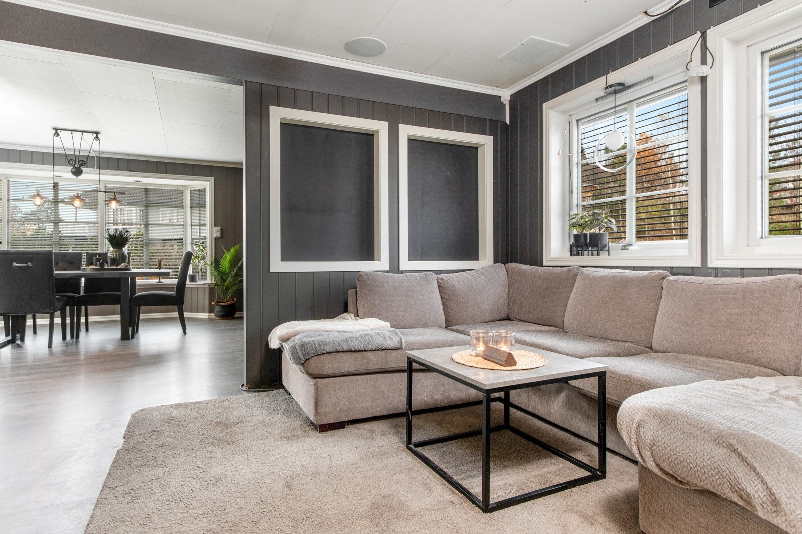 Stuen er et flott rom med laminatgulv, mørkt veggpanel og hvitt listverk som gir en fin kontrast. Galleribilde