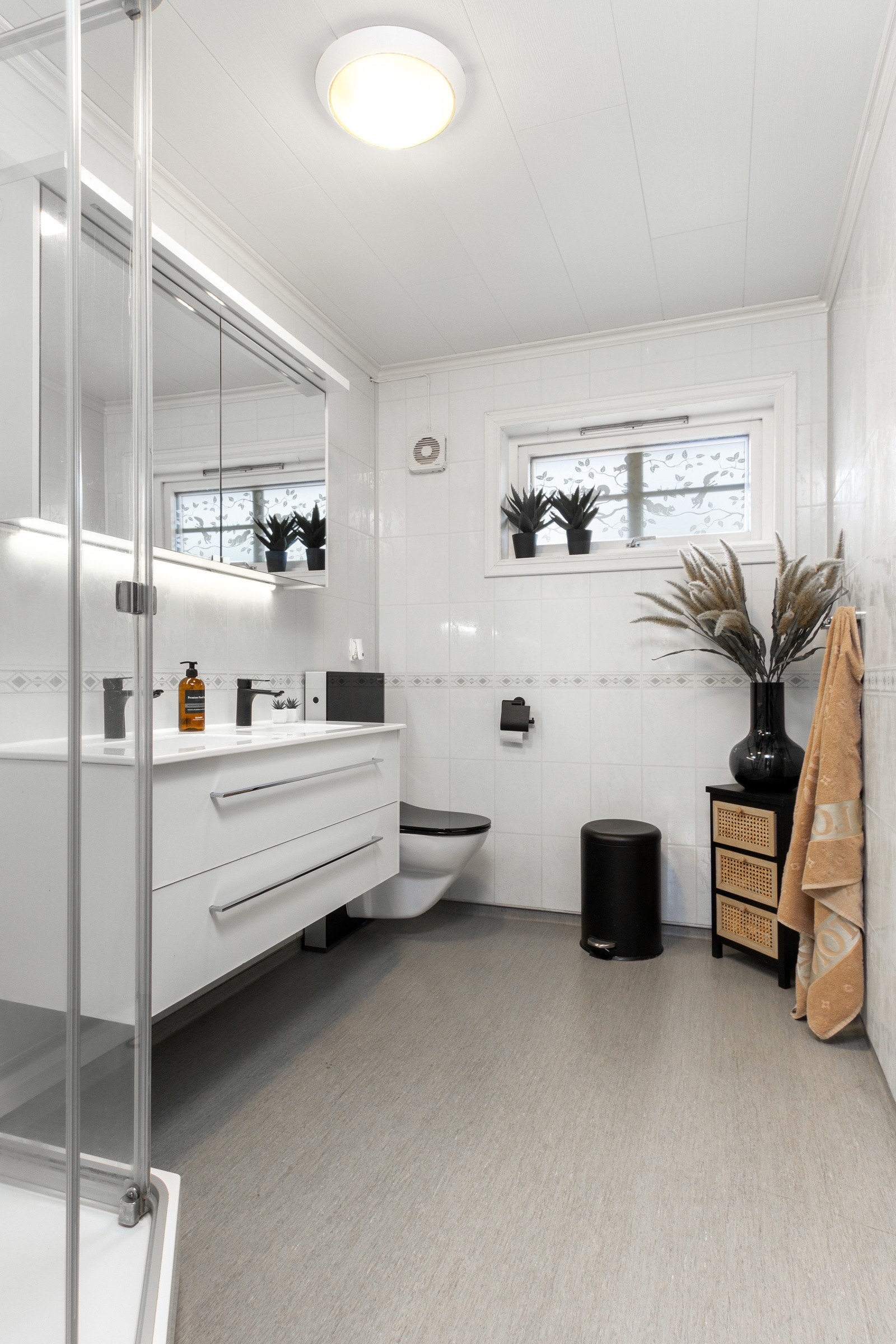 Den hvite innredningen er i moderne stil med to gode skuffer, heldekkende dobbelservant og stort speilskap med belysning. Galleribilde