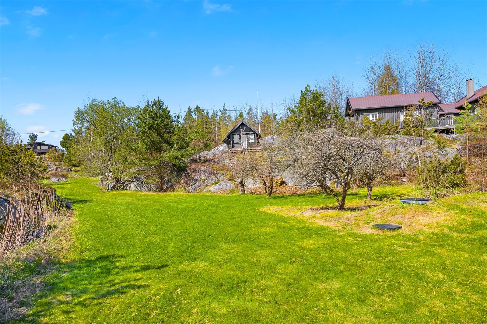 Til eiendommen hører en flott hage opparbeidet med plen. Her finner du prydbusker og gamle frukttrær. Byggene på bildet er naboeiendommer. Området benyttes også av enkelte hytte-eiere. Galleribilde