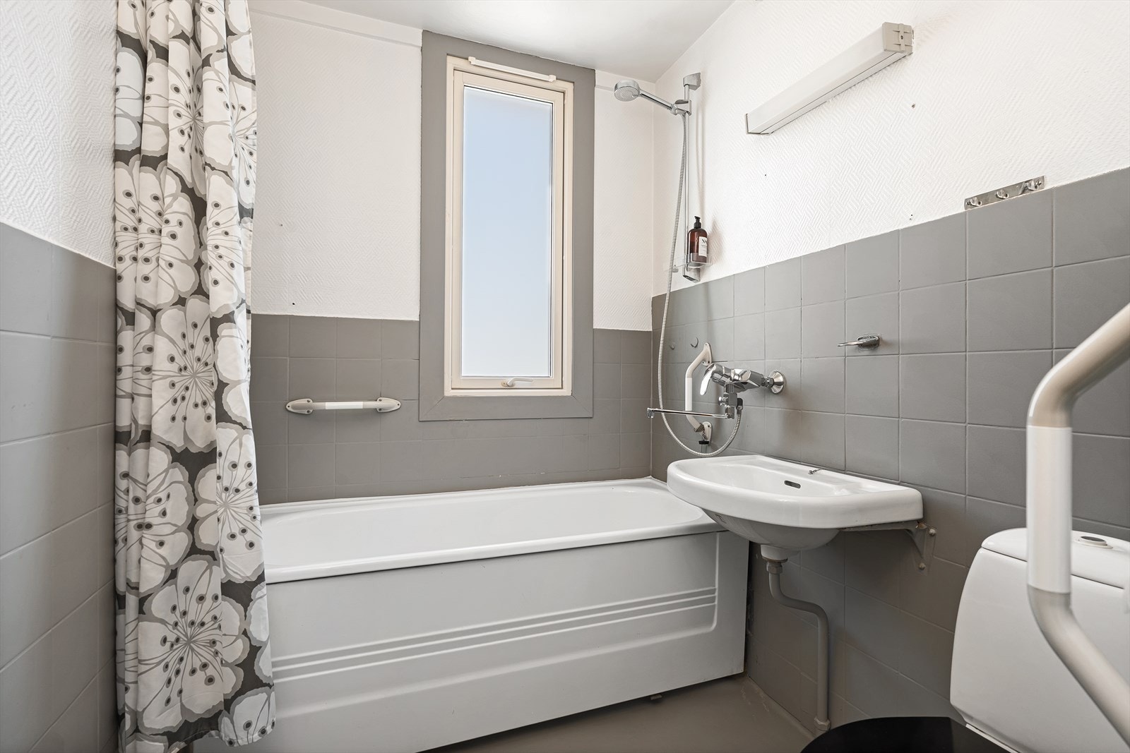 Badet har malt betonggulv og fliser på deler av veggene. Det inneholder et badekar med dusjmuligheter, toalett, samt enkel vask. Galleribilde