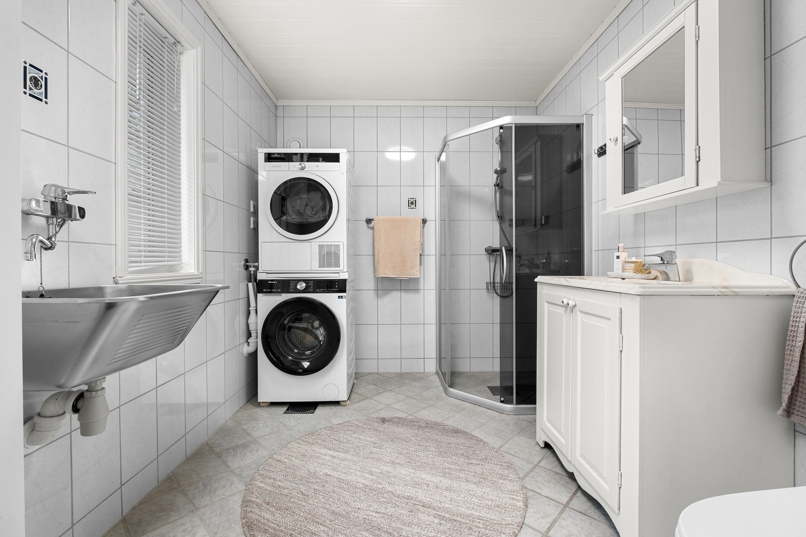 Flislagt bad fra byggeår med behagelig gulvvarme, vegghengt servant, speilskap med overlys, opplegg for vaskemaskin og dusjhjørn Galleribilde