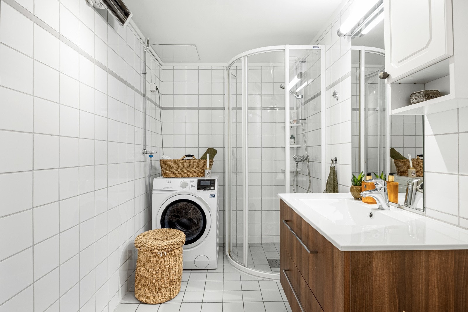 Badet inneholder servantinnredning med speil, dusjhjørne, toalett og opplegg for vaskemaskin Galleribilde