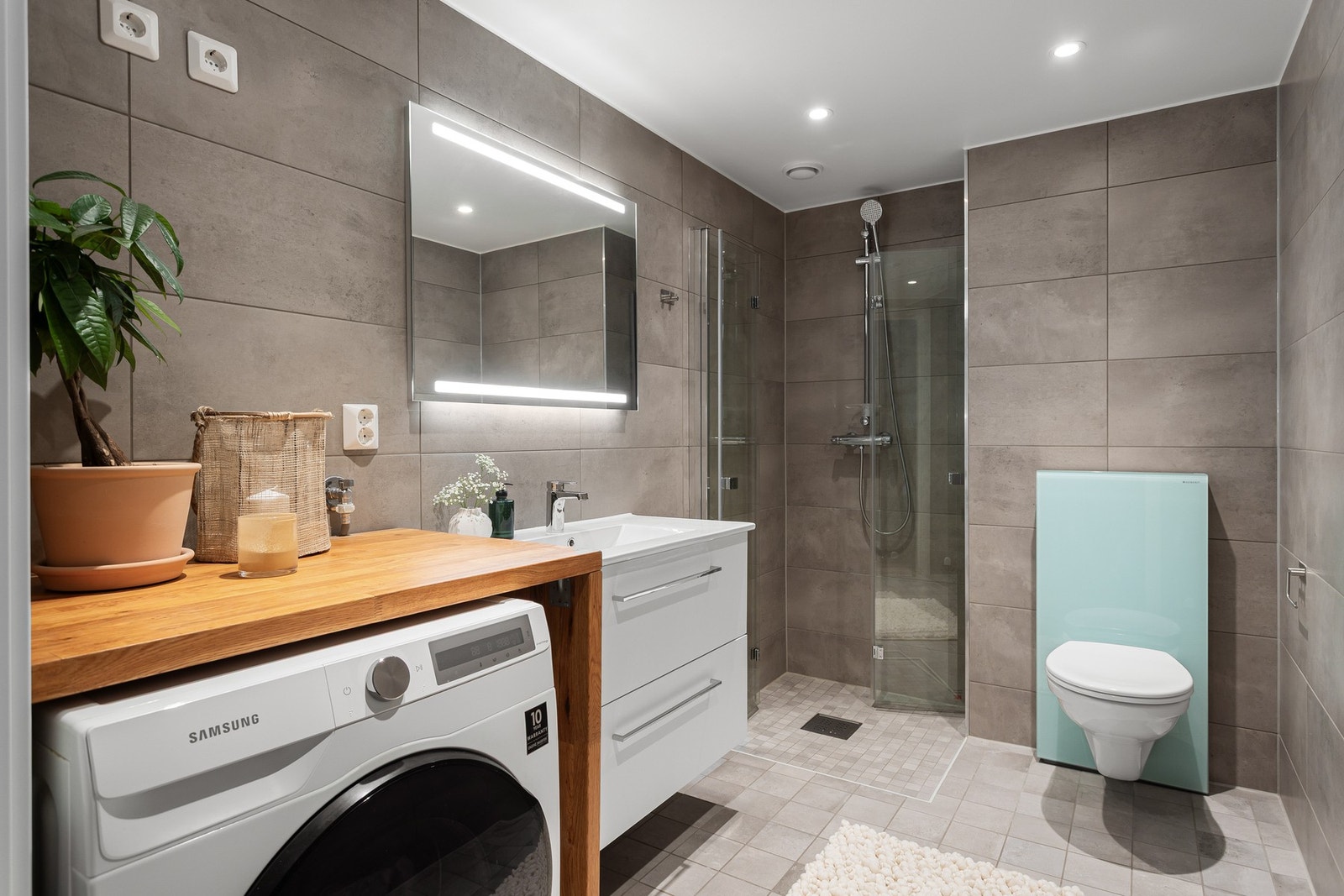 Lekkert, flislagt baderom med inngang fra entréen. Badet har varme i gulv samt downlights i himling. Opplegg for vaskemaskin. Galleribilde