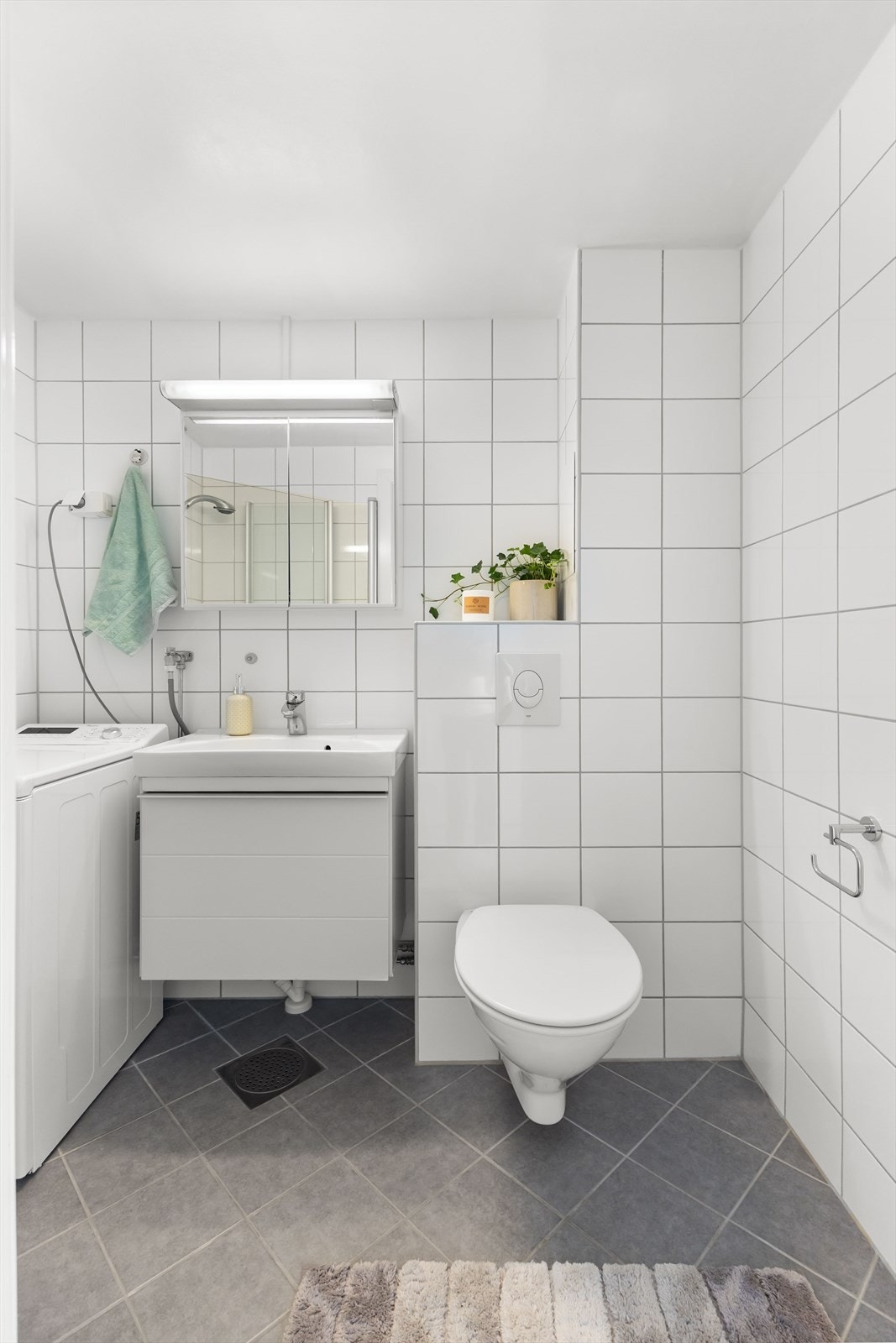 Badet har varme i gulv, servant med innredning, opplegg for vaskemaskin, toalett og dusjhjørne med innfellbare dusjdører Galleribilde