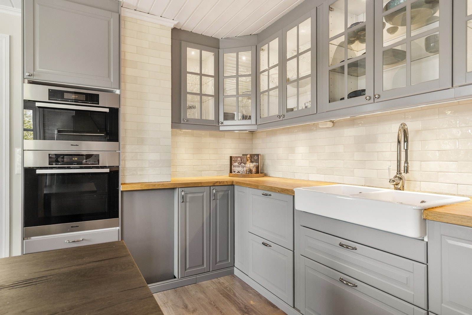 Veggene over kjøkkenbenken er kledd med lyse, glasserte fliser som står godt til resten av interiøret. Galleribilde