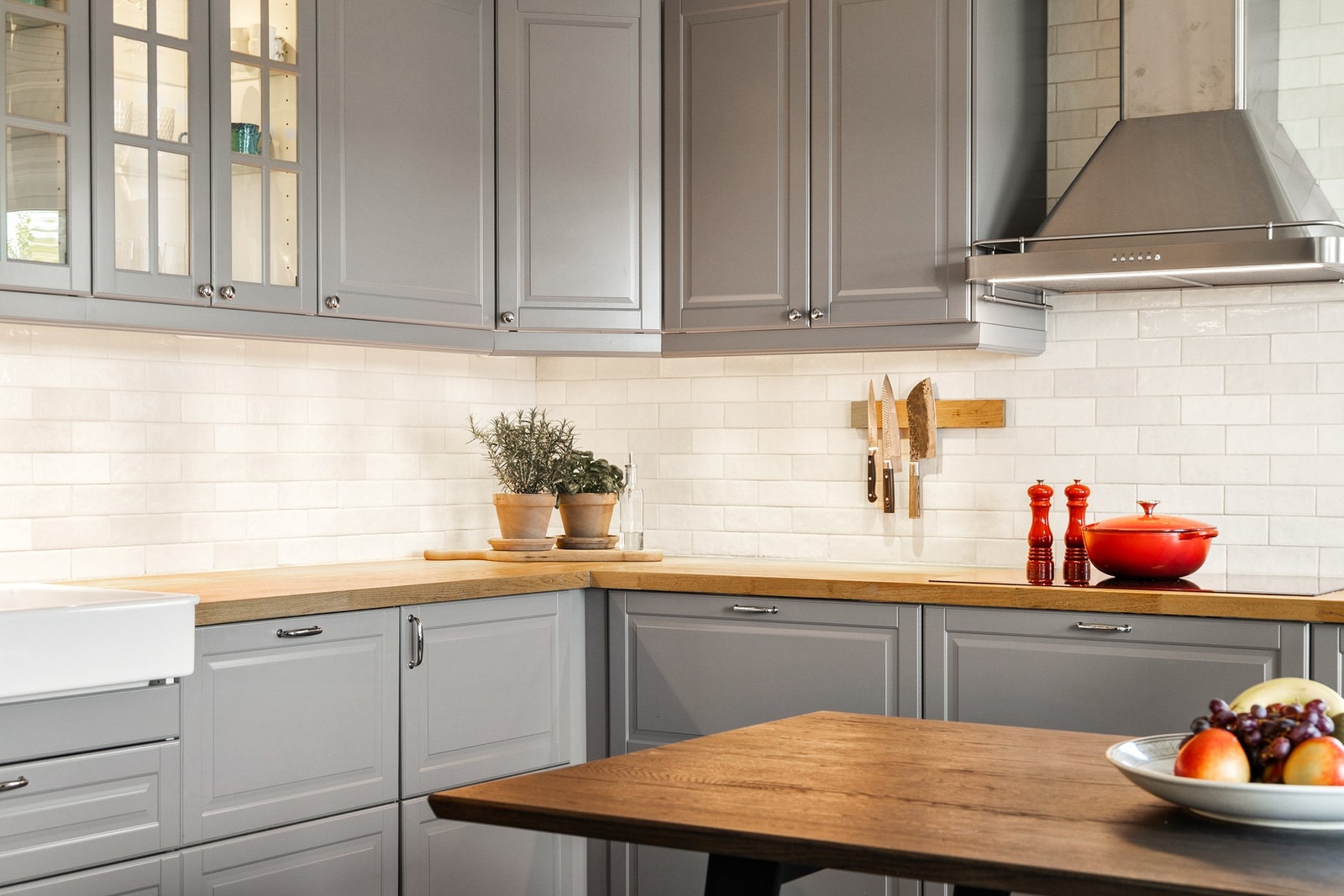 Innredningen har grå, profilerte fronter, vitrinedører, takhøye skap og gyllen, solid heltrebenkeplate. Galleribilde